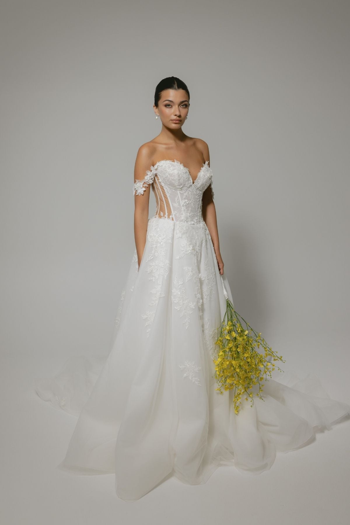 wedding dress featuring off the shoulder straps, sweetheart neckline, sheer boning on the sides, and floral lace A-line skirt