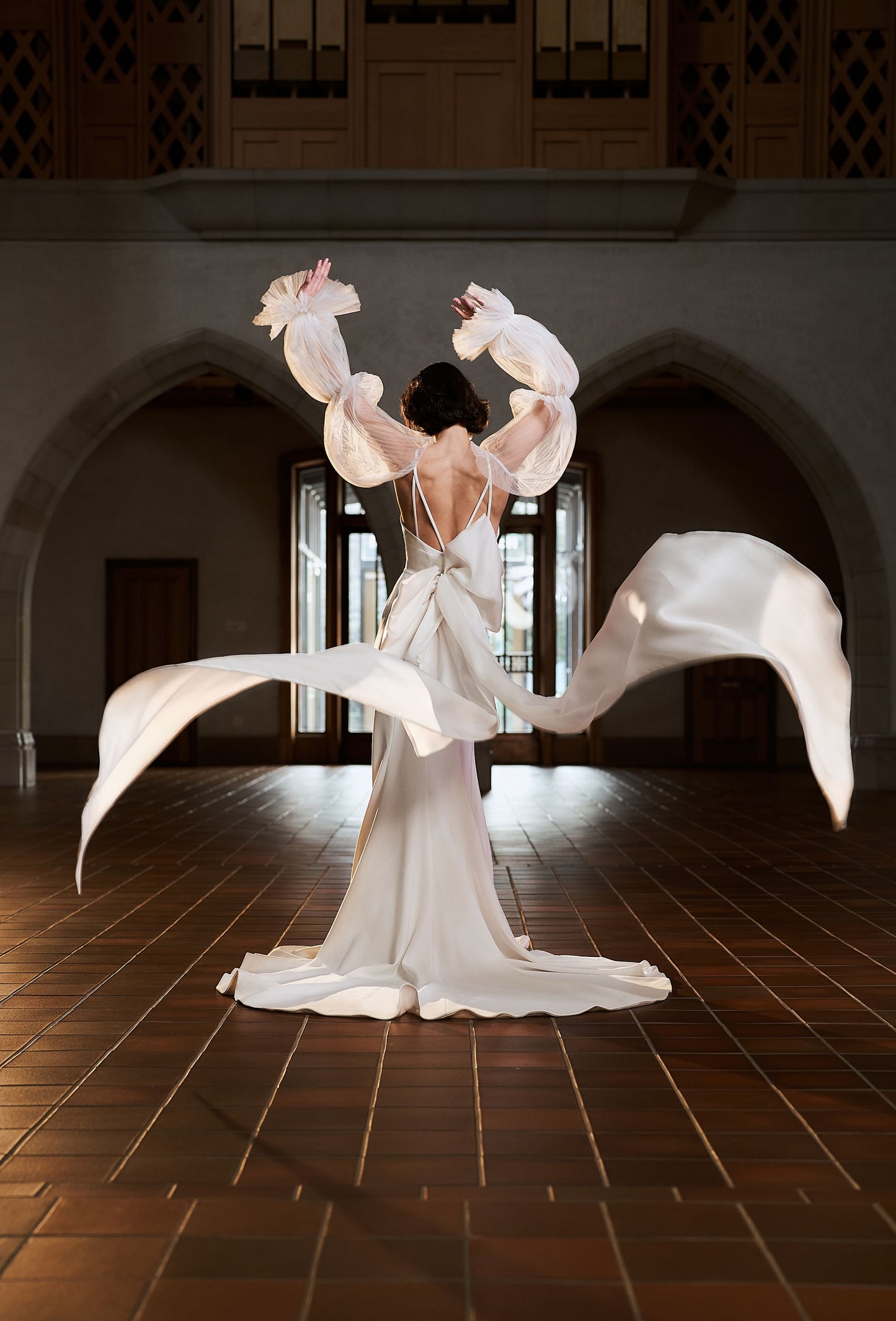 Back view of model wearing Savannah gown with detachable Savannah sleeves. Three tiers of soft pleated tulle is gathered by fine elastic.
