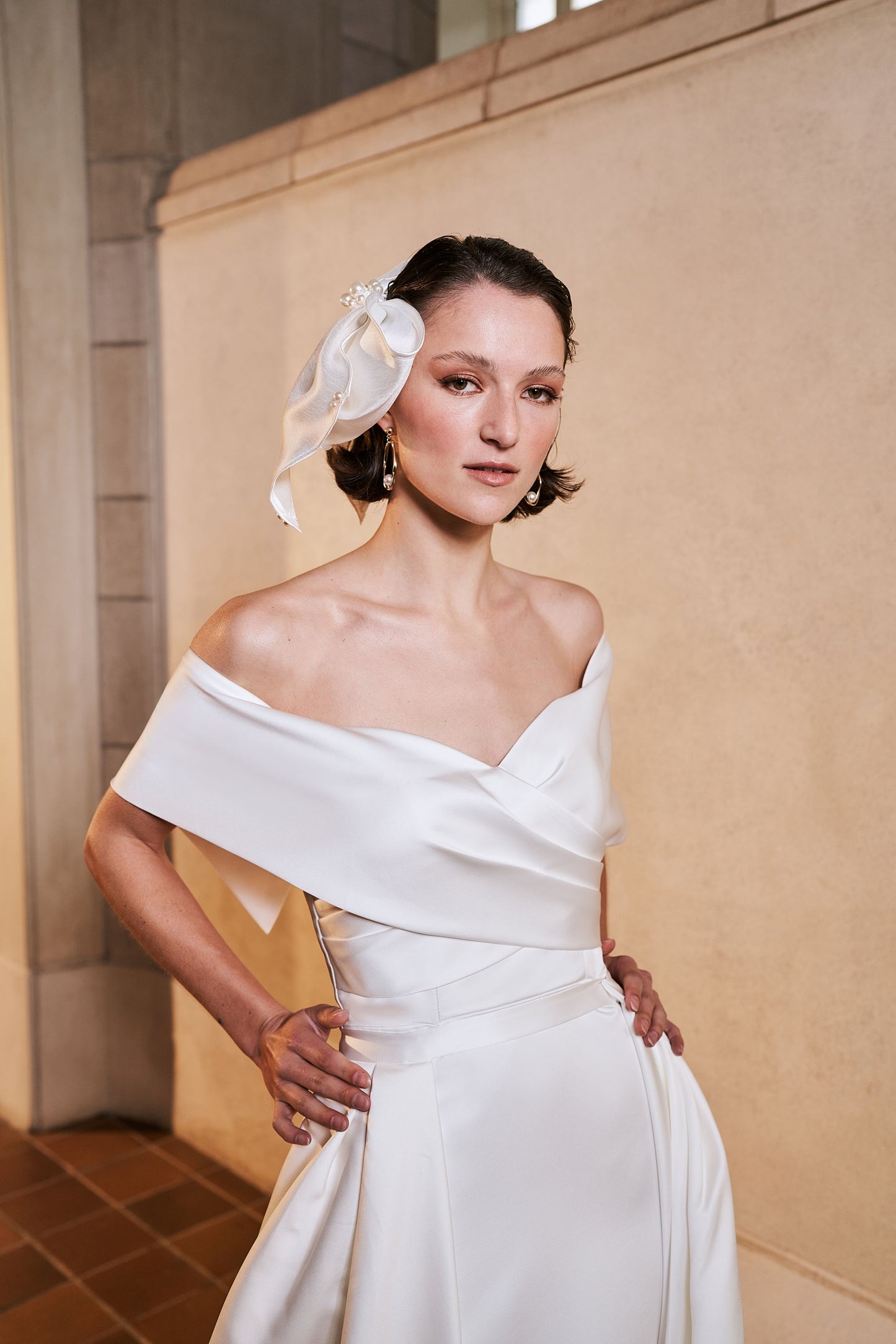 Close up of serenity overskirt attaching at the waist of the Serenity wedding dress. Ivory satin that pleats into a satin waistband joins it seamlessly into the gown.
