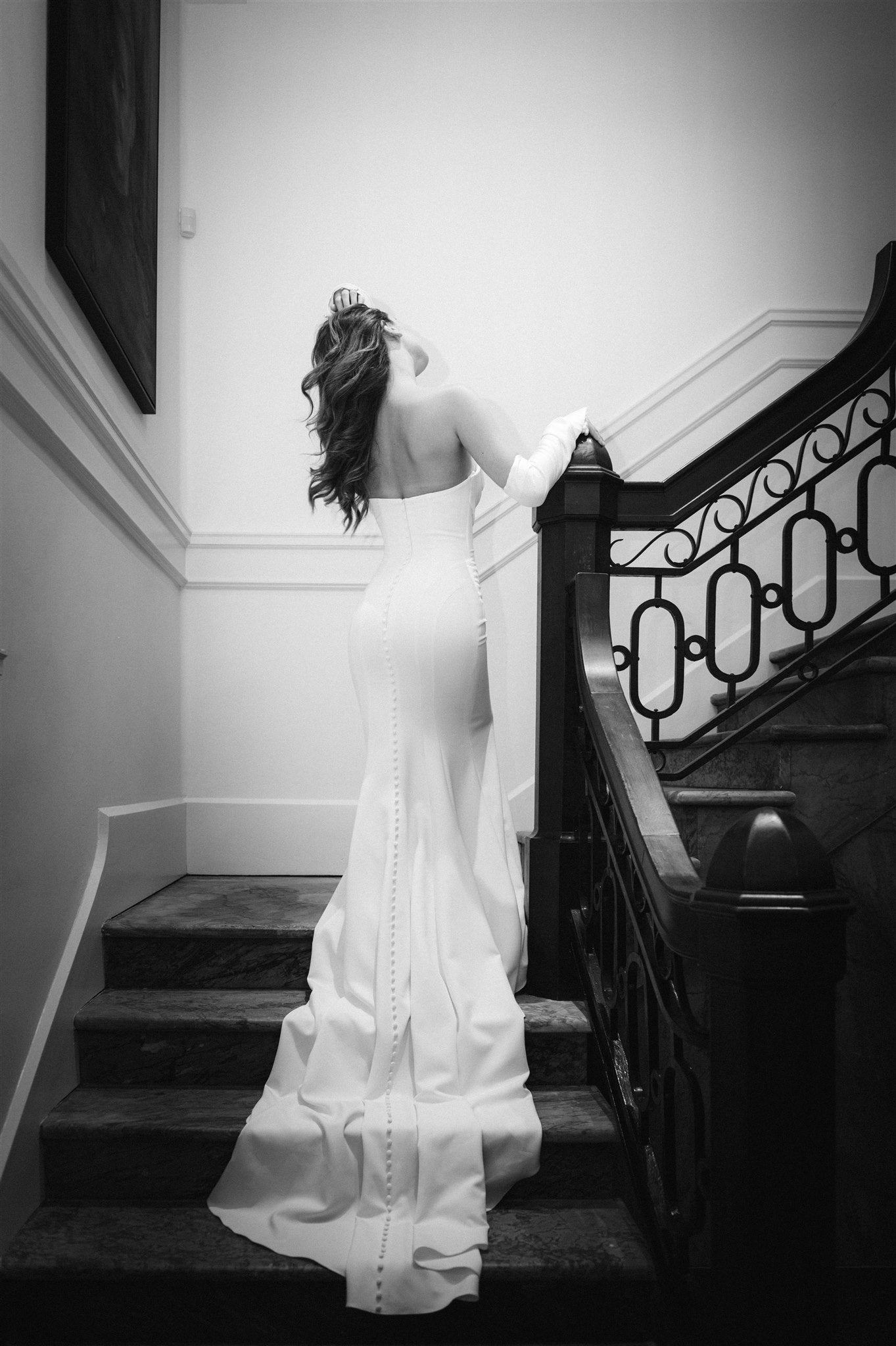 Back view of Tina dress draping down stairwell. Covered buttons extend length of train