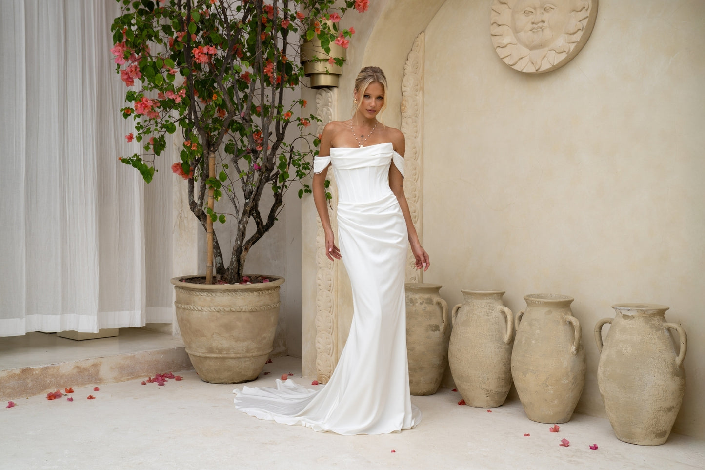 fitted wedding gown with ruched bust, corset boning, and draping across the hips. paired with detachable off the shoulder cap sleeves with pearls. plain fabric, minimal vibes.