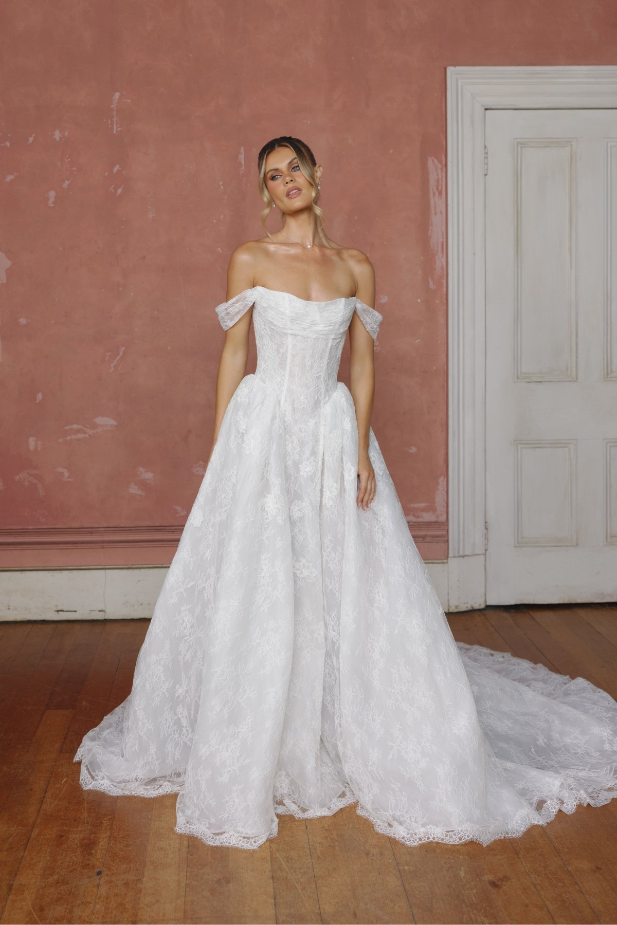 off the shoulder A-line wedding gown in lace, steep basque waist and ruched bust.