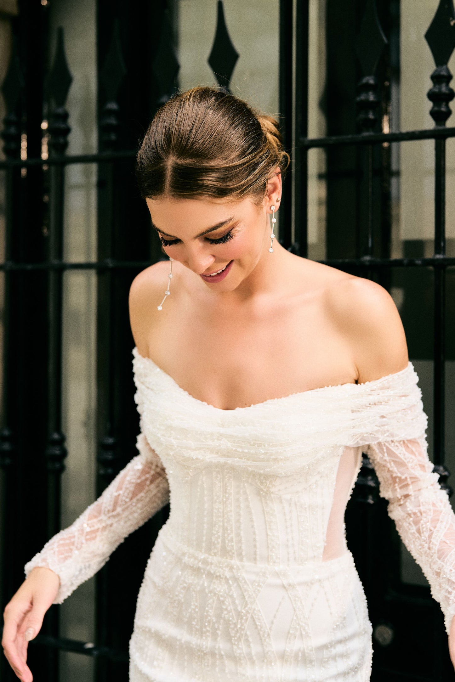 Close up of beaded bodice. Off-the-shoulder neckline with sheer sleeves and sheer mesh panels at waist.