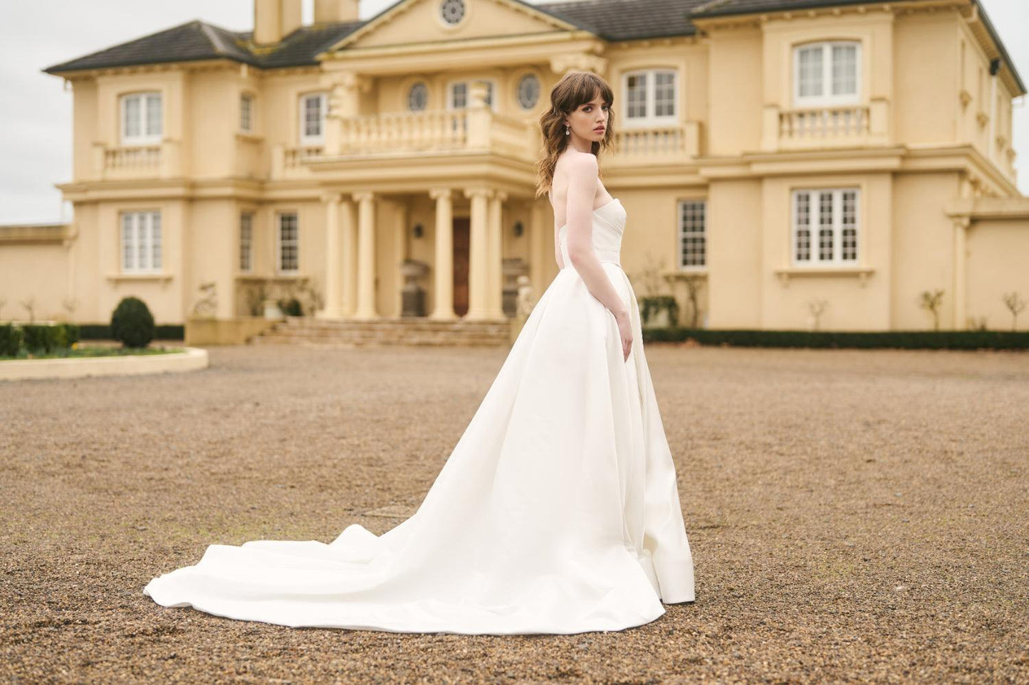 Side view of Daisha dress. Strapless bodice cinched at waist with dramatic train. Made entirely from Ivory satin.