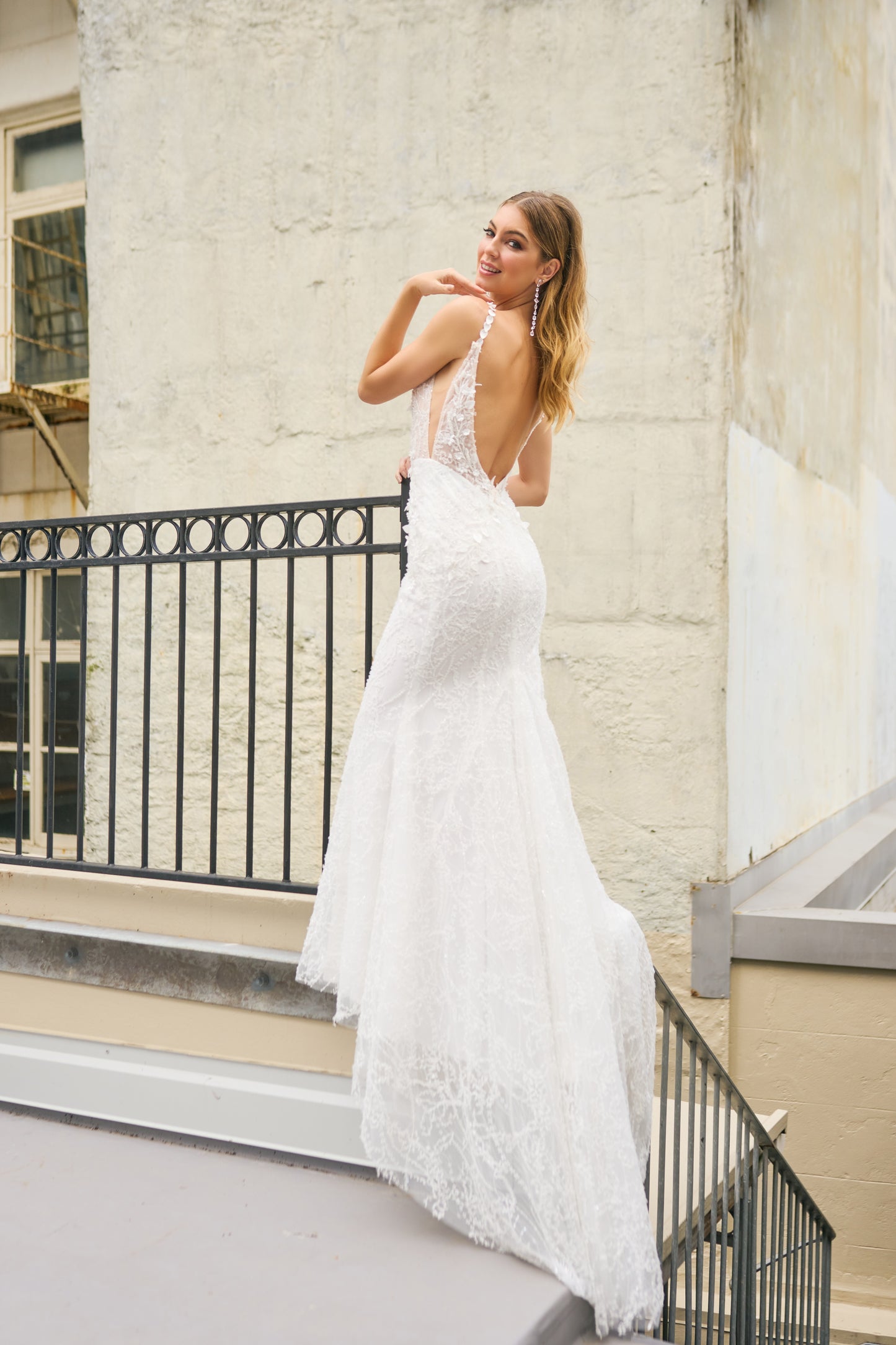 Rochelle wedding dress with mermaid silhouette, beaded and glittery fabric, plunging neckline, low-open back, and leaf detailing on the straps for a modern touch.