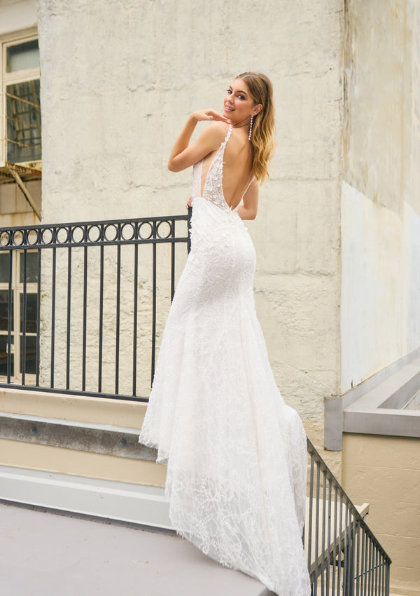 Rochelle wedding dress with mermaid silhouette, beaded and glittery fabric, plunging neckline, low-open back, and leaf detailing on the straps for a modern touch.