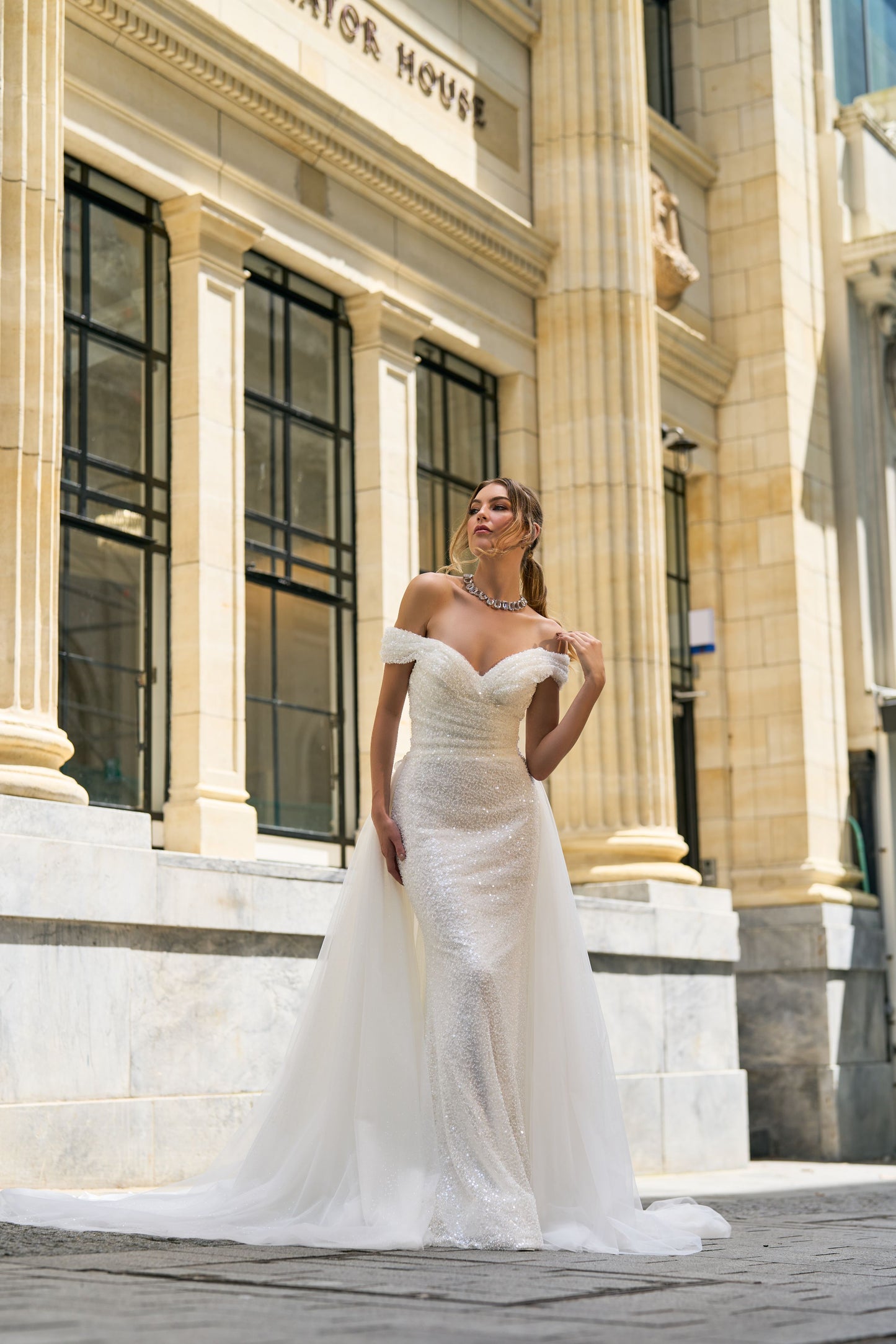 Fully beaded off-the-shoulder dress. Fit and flare style with rouching on bust and waist. Soft detachable overskirt.