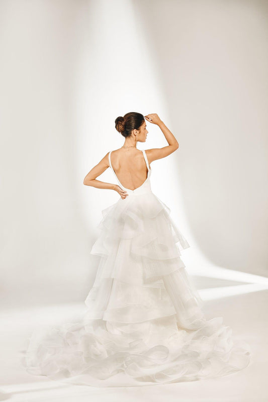 Back view of olivia overskirt in layers of tulle with horsehair hems, creating ruffled aesthetic. A voluminous detachable overskirt with ruffled train.