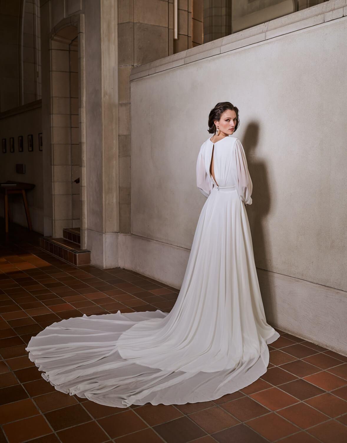Model wearing Serena wedding dress with long sleeves and a flowing skirt from the Royal collection