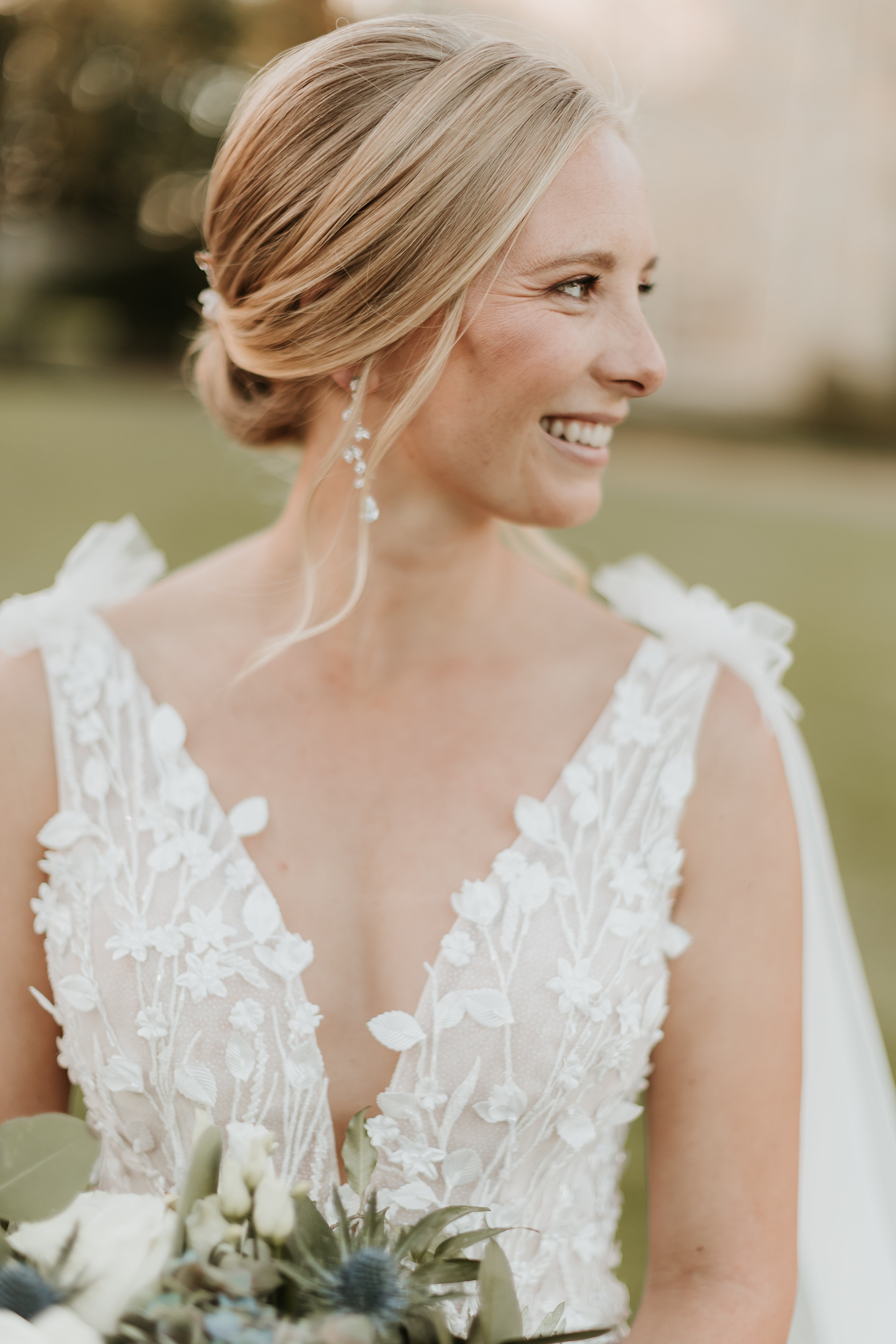 Close up of smiling bride wearing SAige gown. Plunging v-neck with 3D florals and leaves