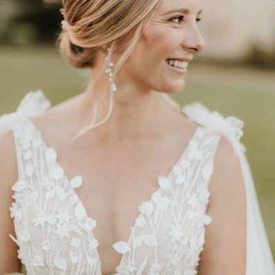 Close up of smiling bride wearing SAige gown. Plunging v-neck with 3D florals and leaves