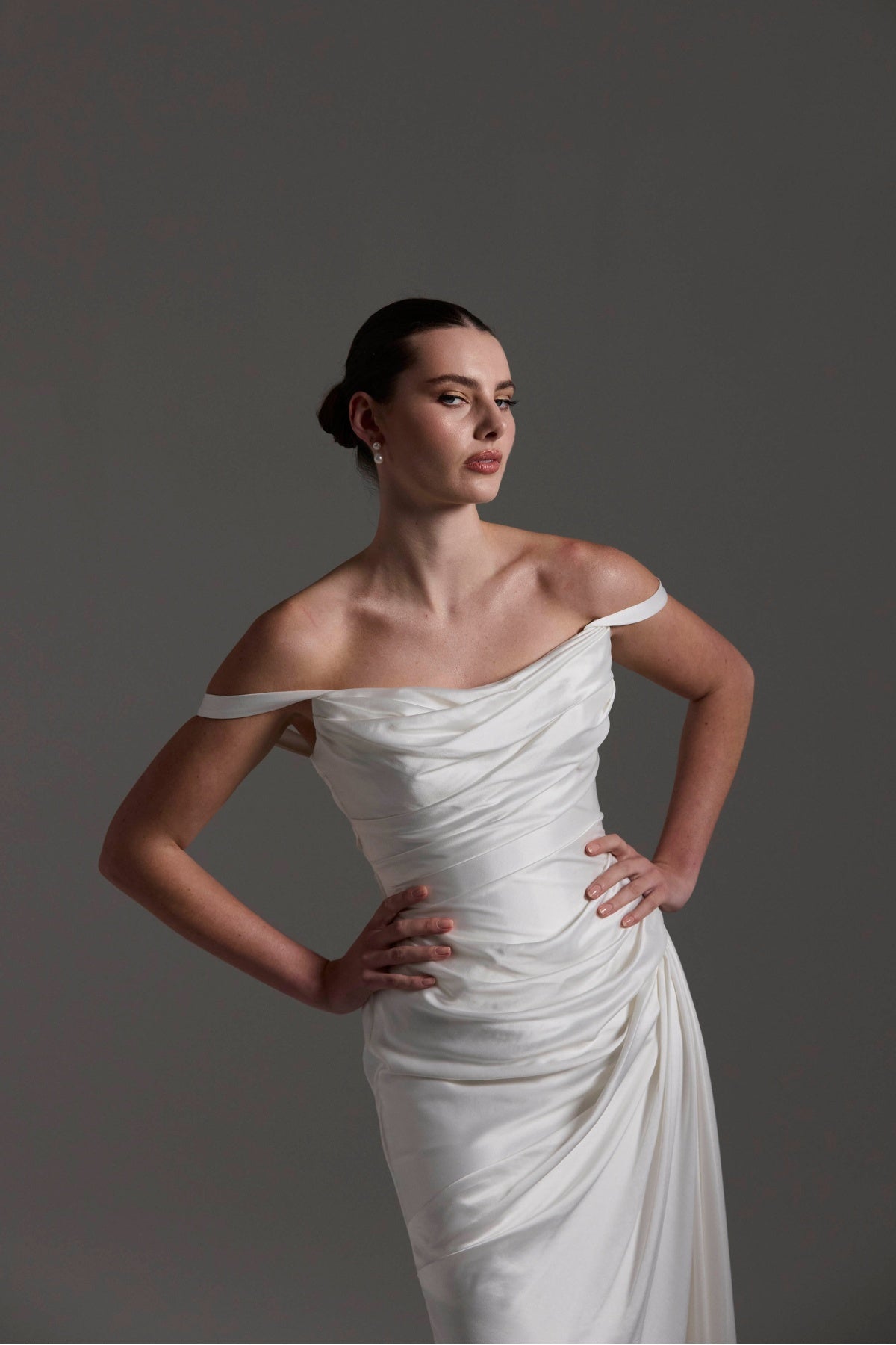 fitted satin wedding dress with pleats across bust and hips. Featuring off the shoulder straps. 