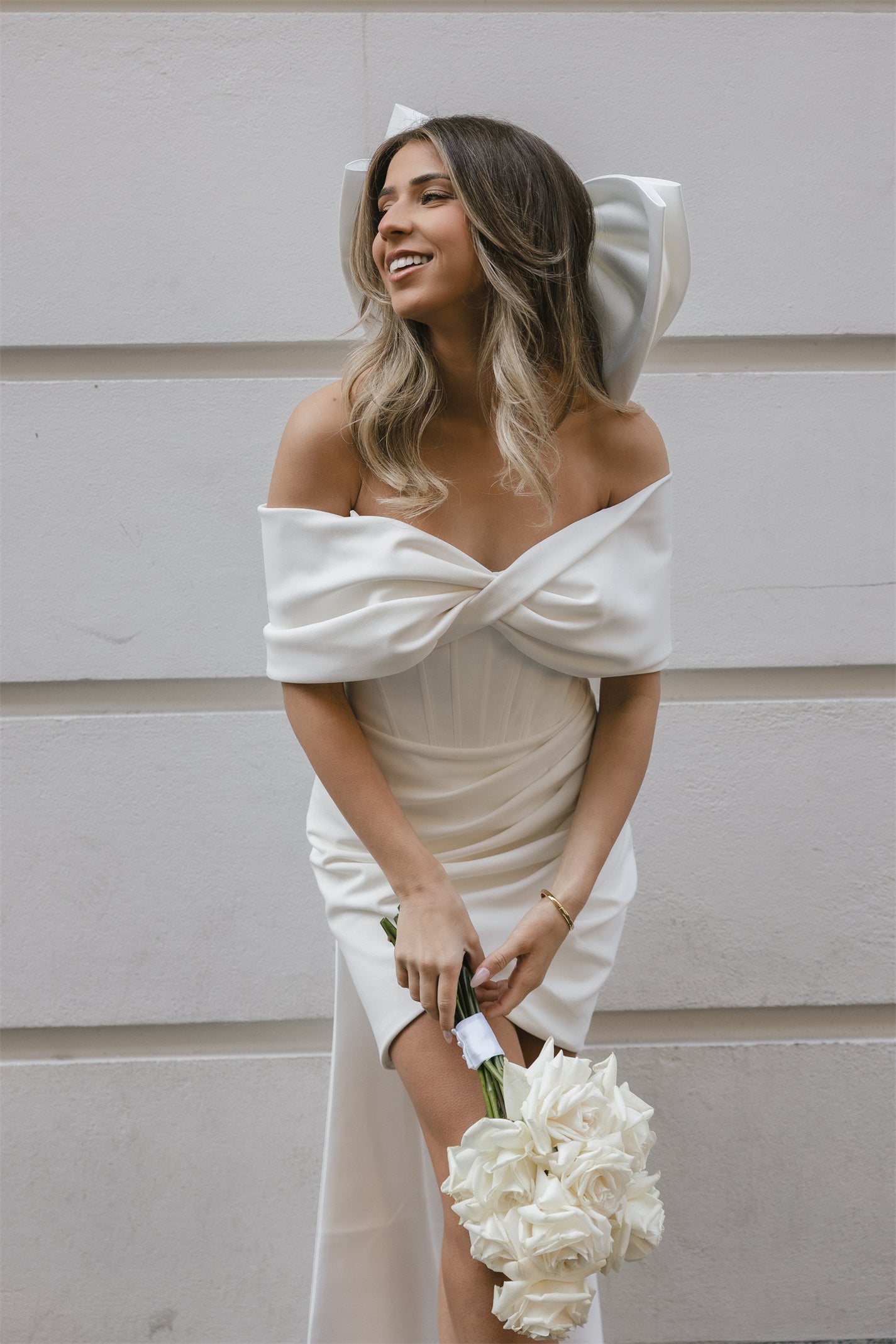 Mini Bridal dress with off-the-shoulder draped sleeves flowing into a full corset bodice, draping into a criss-cross pencil skirt. 