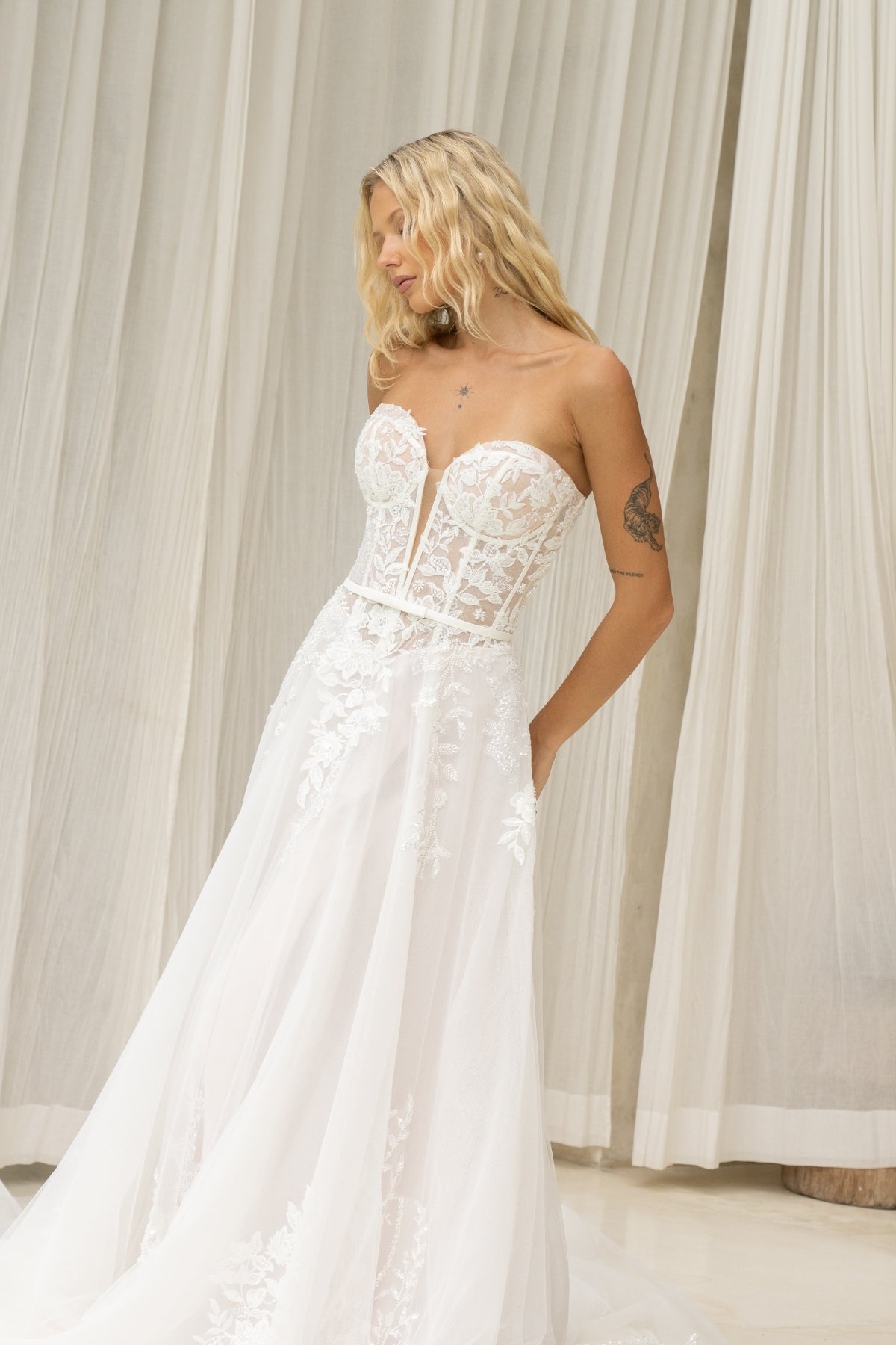 A-line wedding dress with v-plunge sweetheart neckline, floral lace, waistbelt and subtle basque waist, flowing tulle skirt. 