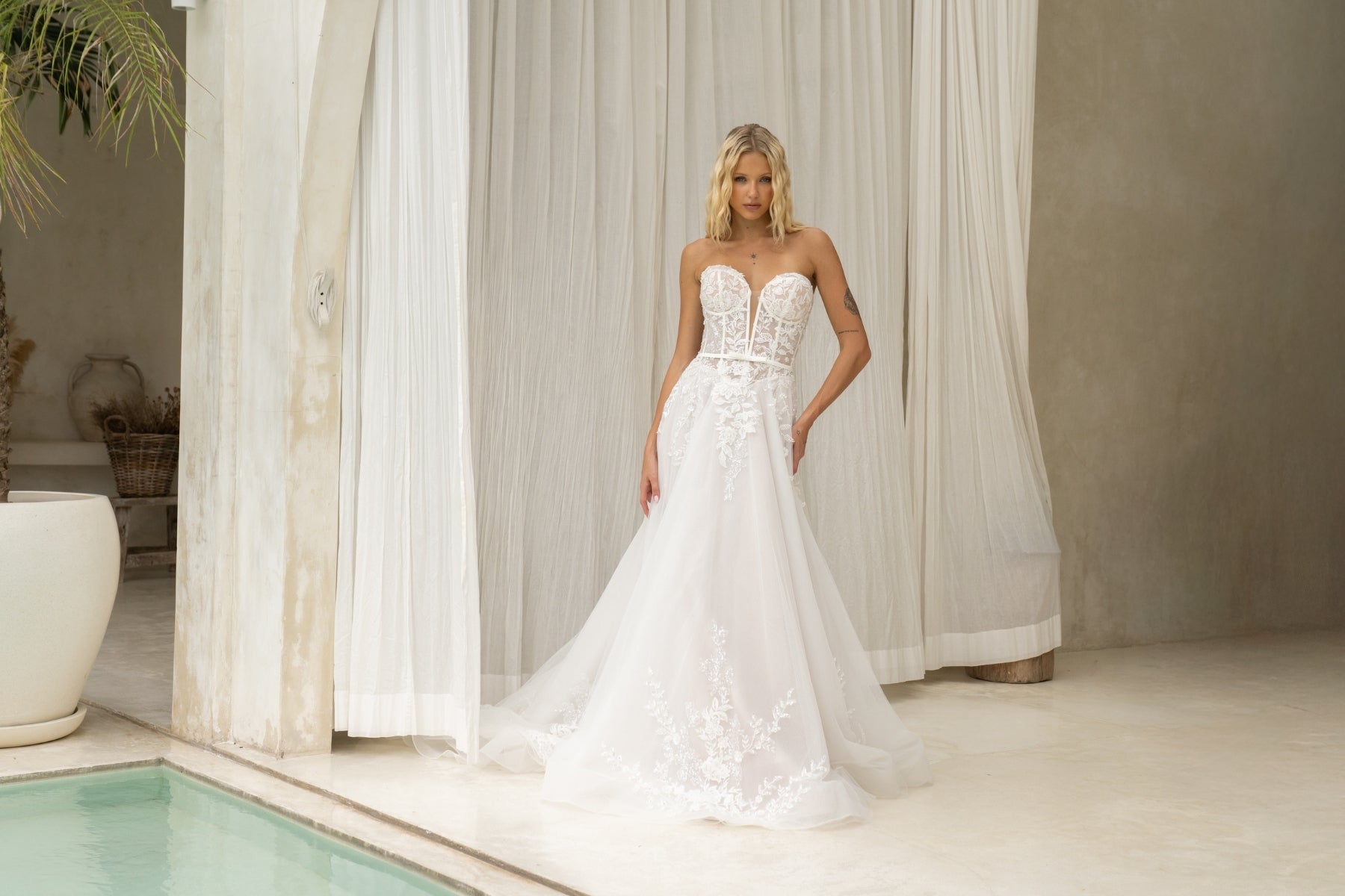 A-line wedding dress with v-plunge sweetheart neckline, floral lace, waistbelt and subtle basque waist, flowing tulle skirt. 
