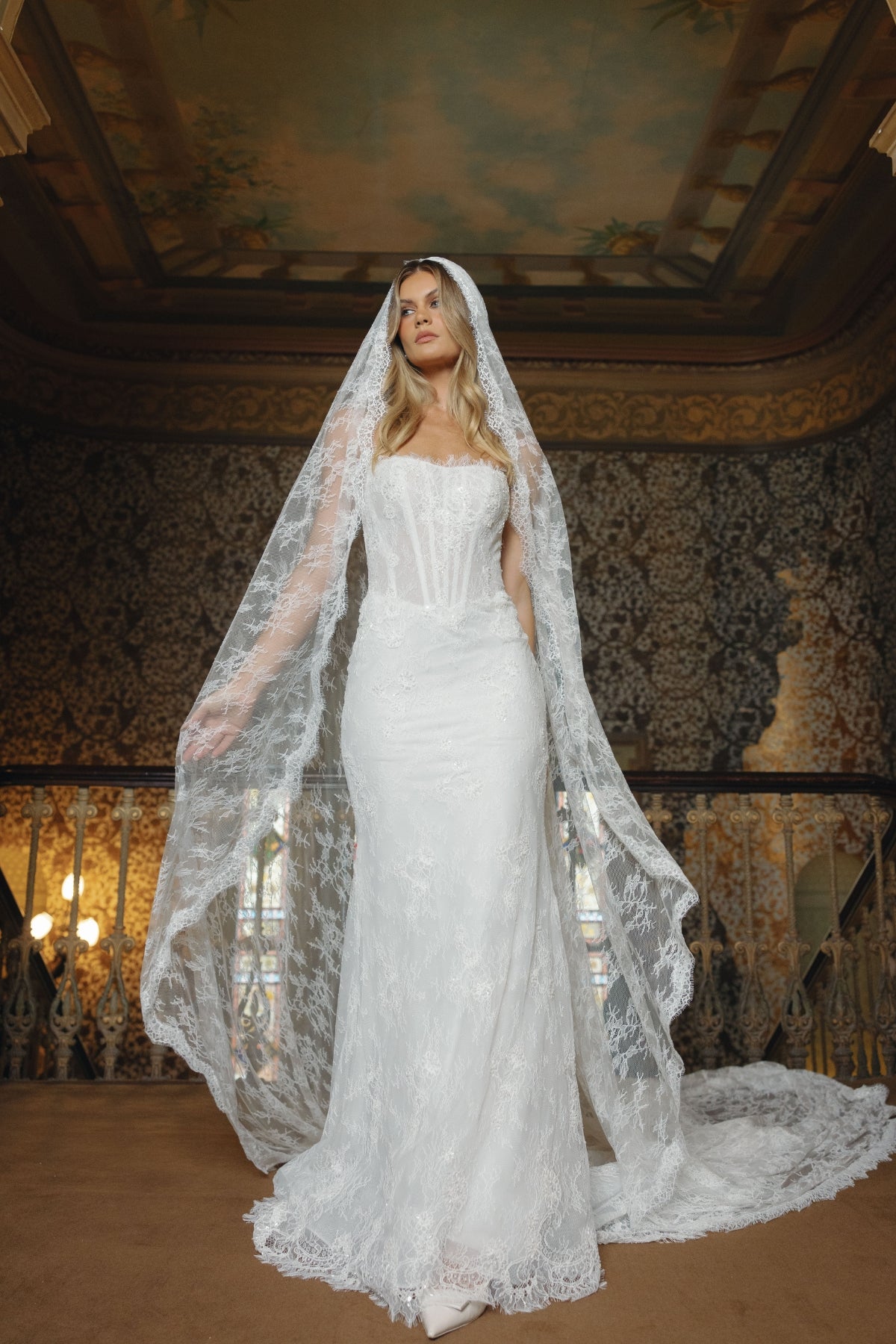 Fitted lace bridal gown featuring a cateye neckline, scalloped lace train. 