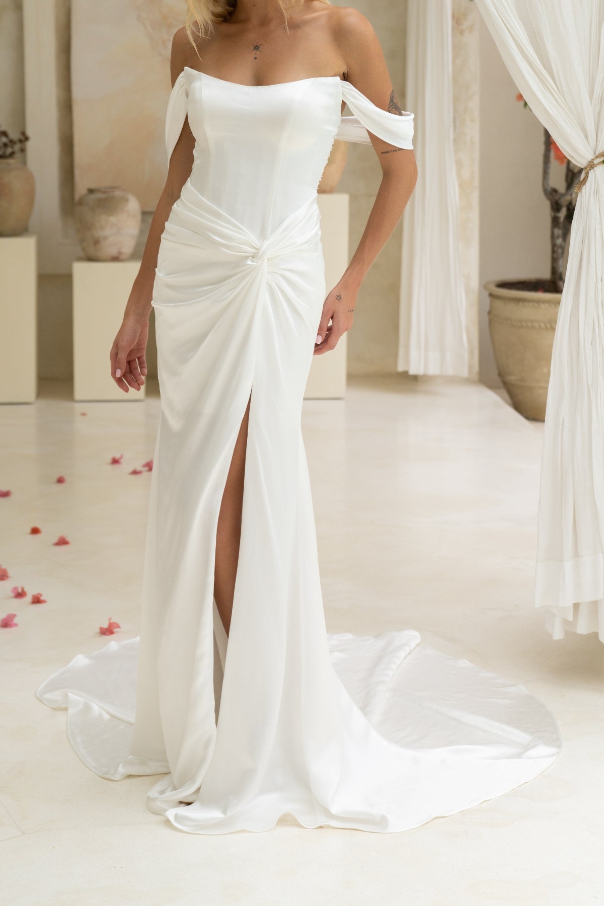fitted wedding gown, with off the shoulder cap sleeves, and a tied ruched knot around the hips, high split. 