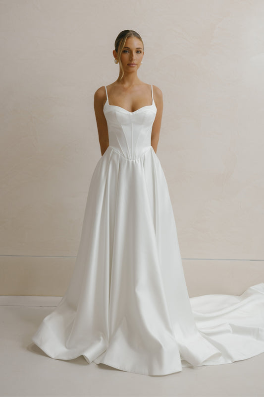 A-line Wedding gown in Satin, thin shoulder straps, corseted bodice with basque waistline. 