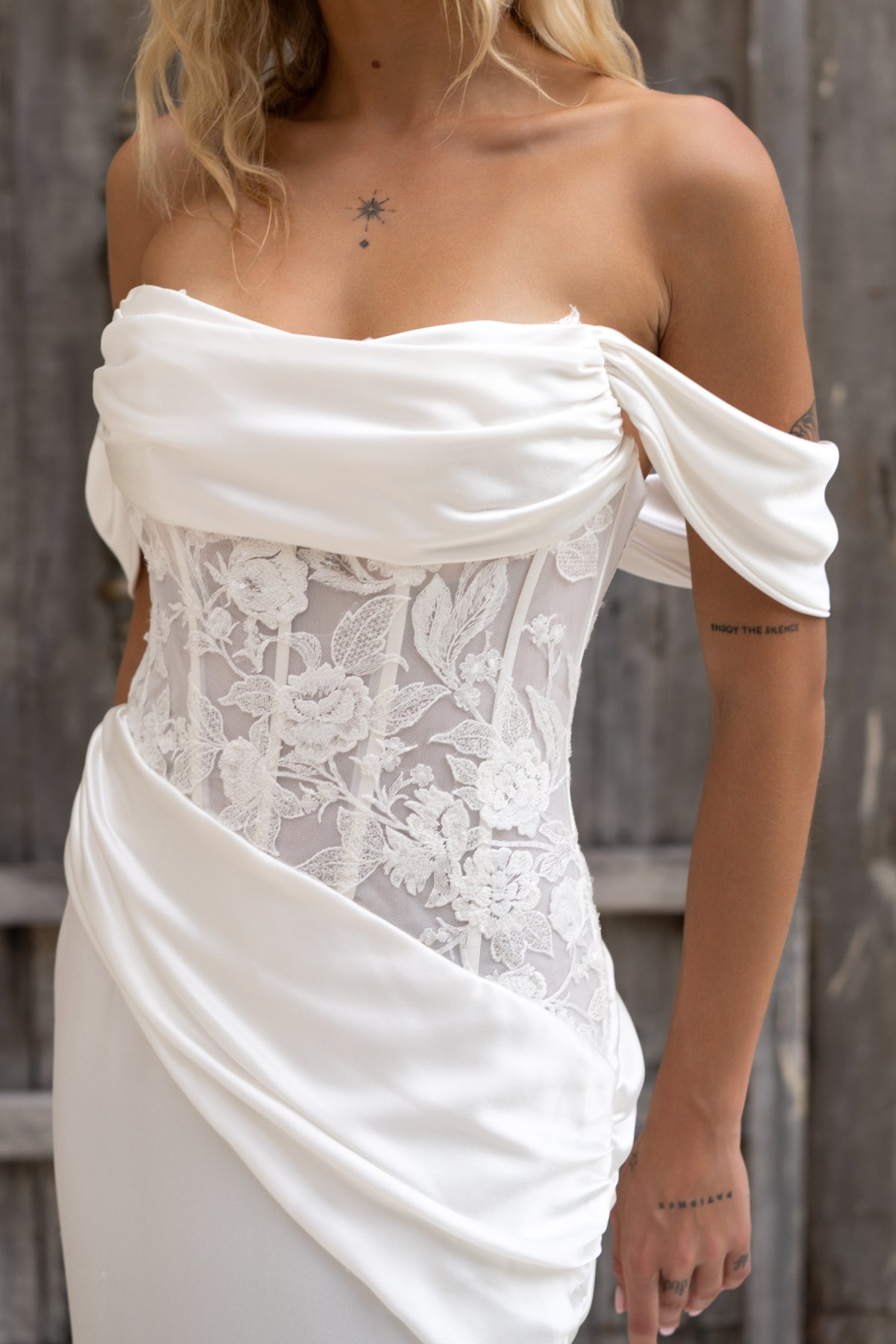 fitted wedding gown with satin ruching drape across the bust and hips, floral lace covered torso, and satin skirt. with off the shoulder cap sleeves. 