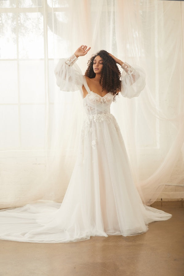 Model wears soft tulle Sky gown with detachable Sky Sleeves, a soft tulle balloon sleeve with floral applique cuffs.