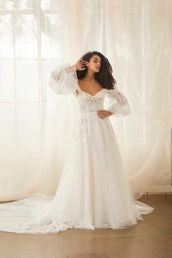 Model wears sky wedding dress with detachable balloon sleeves made from soft tulle with floral applique cuffs