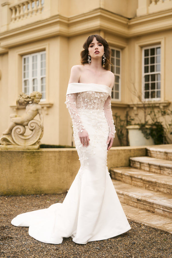 Model wears Theia gown with detachable sleeves made from matching lace. Sleeves fit under off-the-shoulder dress.