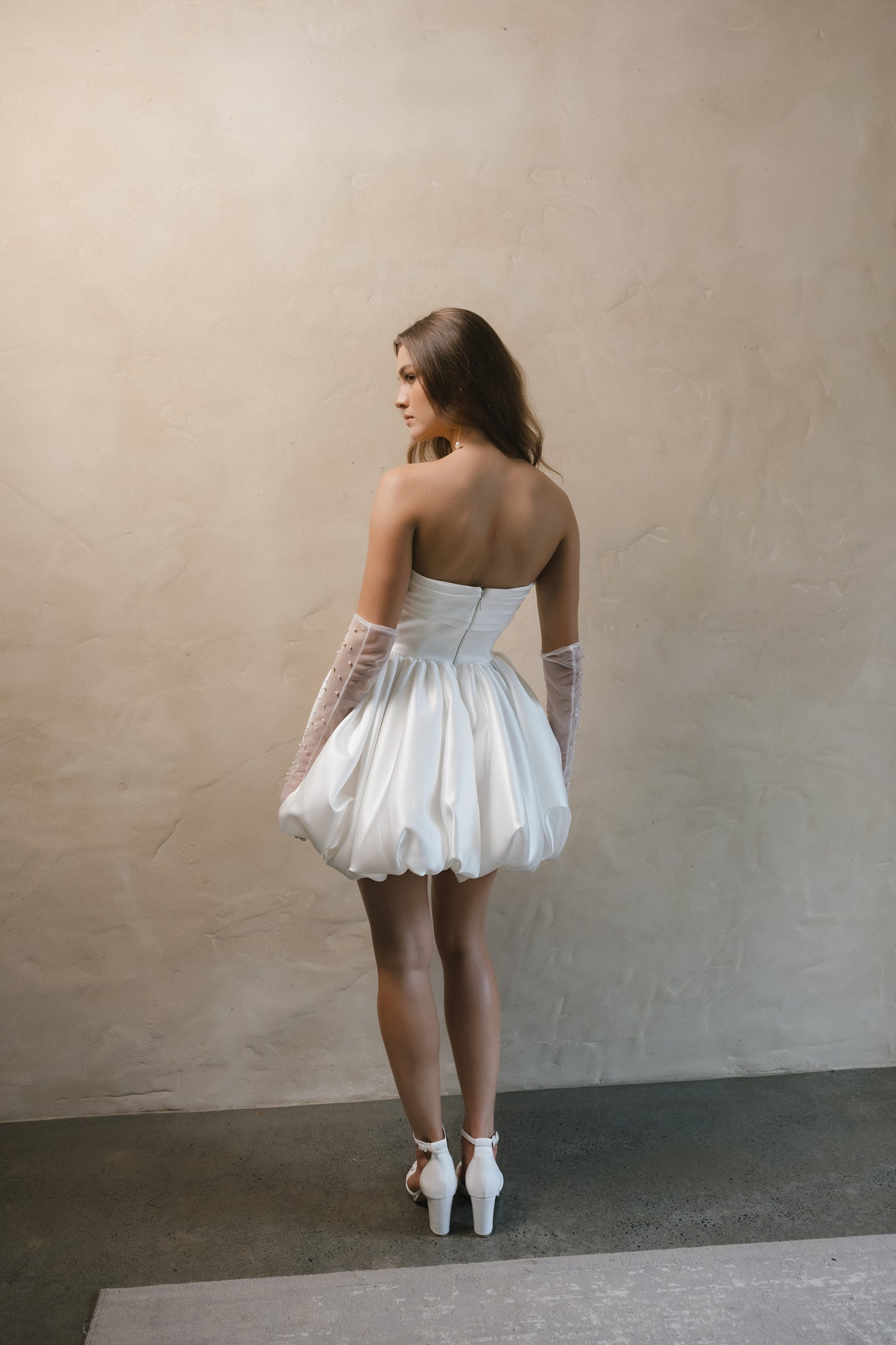 Bridal gown Brittany features a pearl-encrusted corset bodice, ruffled bubble skirt, and underbust ruching for a flattering lift. Designed for the chic, fashion-forward bride by Roselle Collection Jessica Couture.