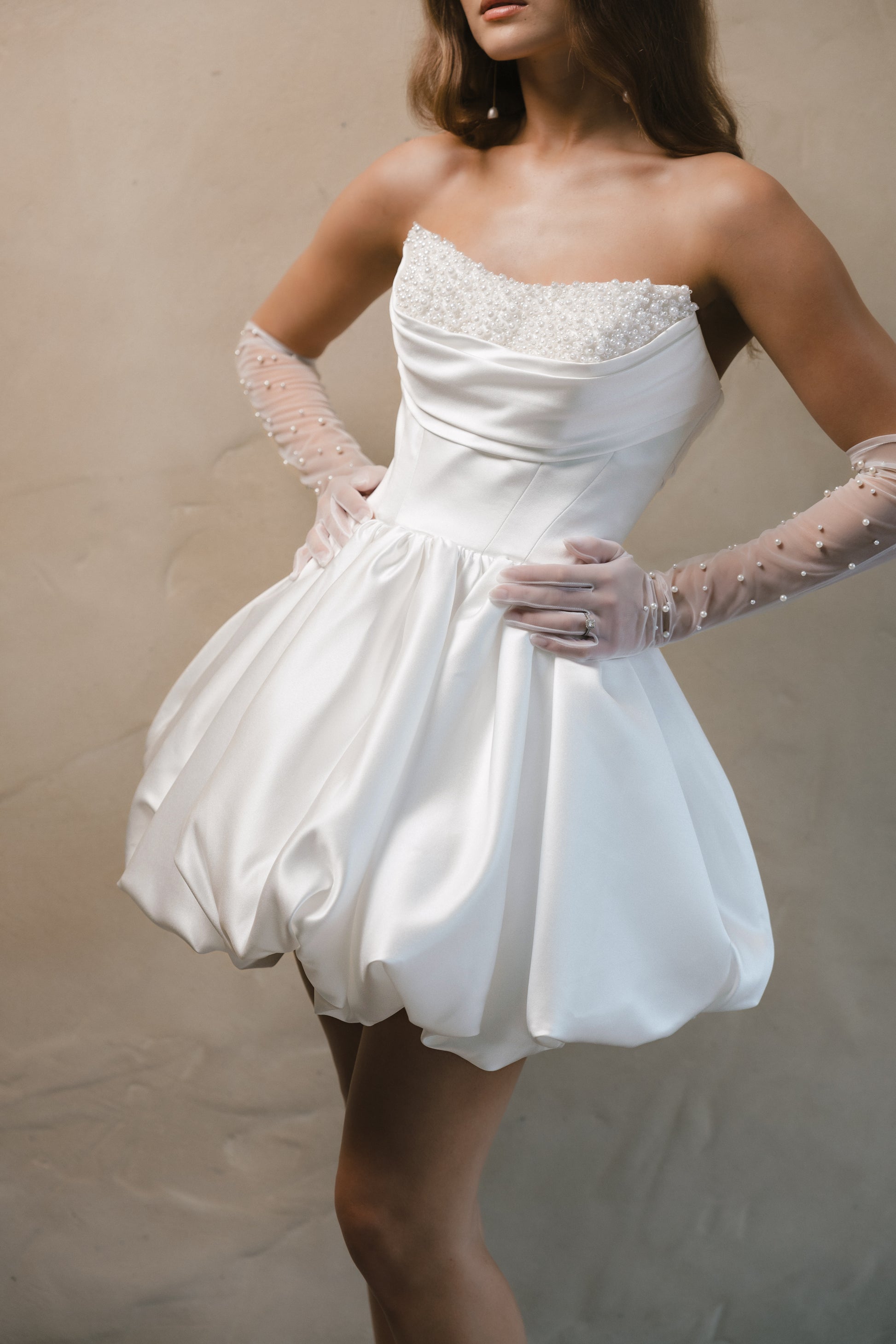 Bridal gown Brittany features a pearl-encrusted corset bodice, ruffled bubble skirt, and underbust ruching for a flattering lift. Designed for the chic, fashion-forward bride by Roselle Collection Jessica Couture.