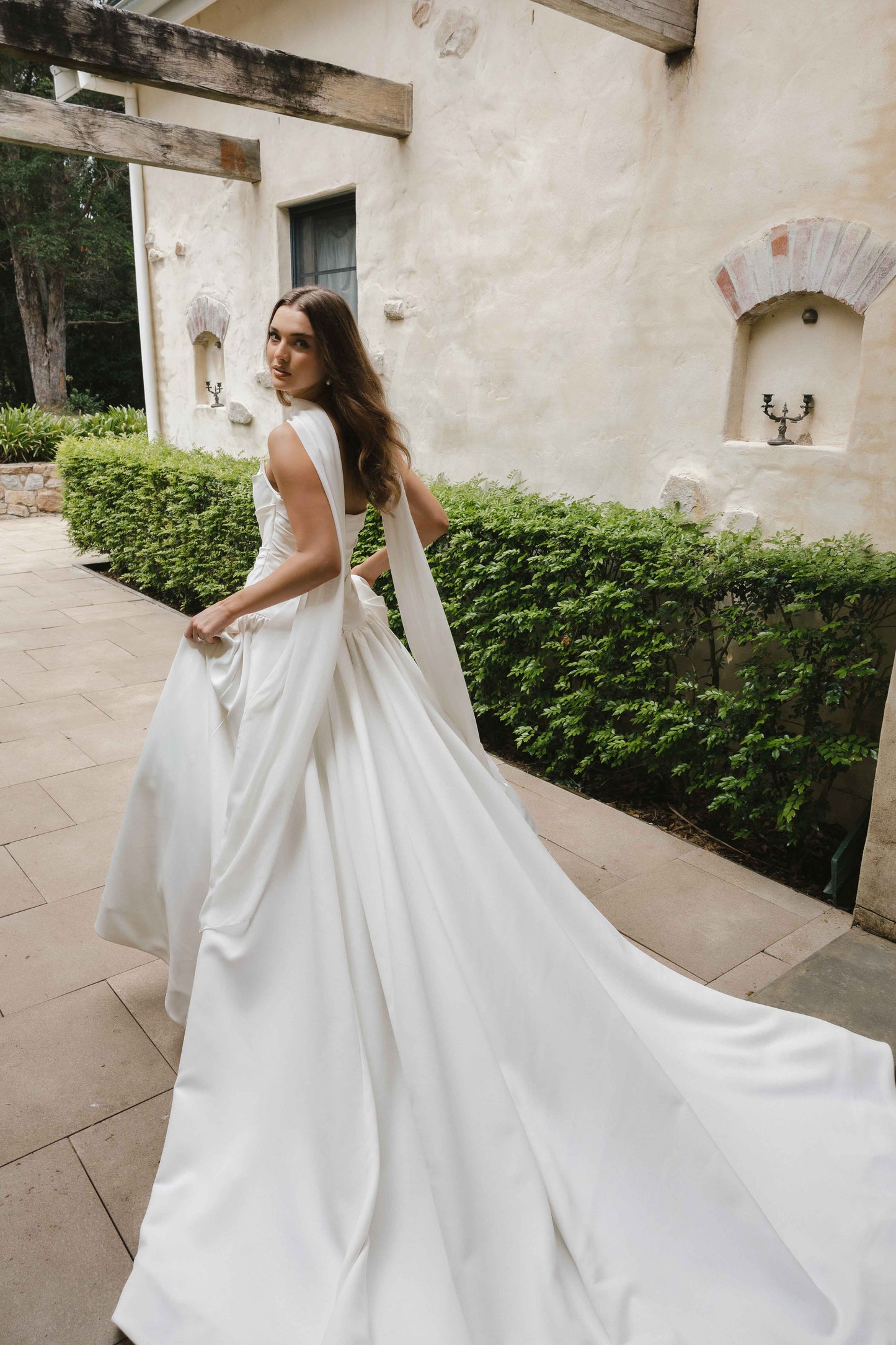 Jana Gown – A-line drop-down waist silhouette with a cat-eye bodice and draped ruching, paired with the Tonica scarf. By Roselle Collection, Jessica Couture.