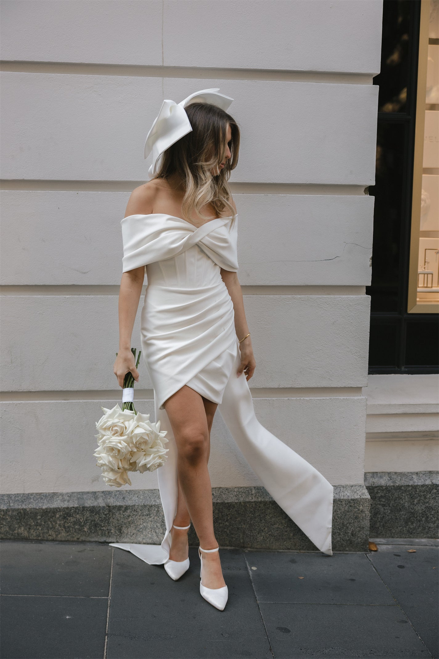 Mini Bridal dress with off-the-shoulder draped sleeves flowing into a full corset bodice, draping into a criss-cross pencil skirt. 