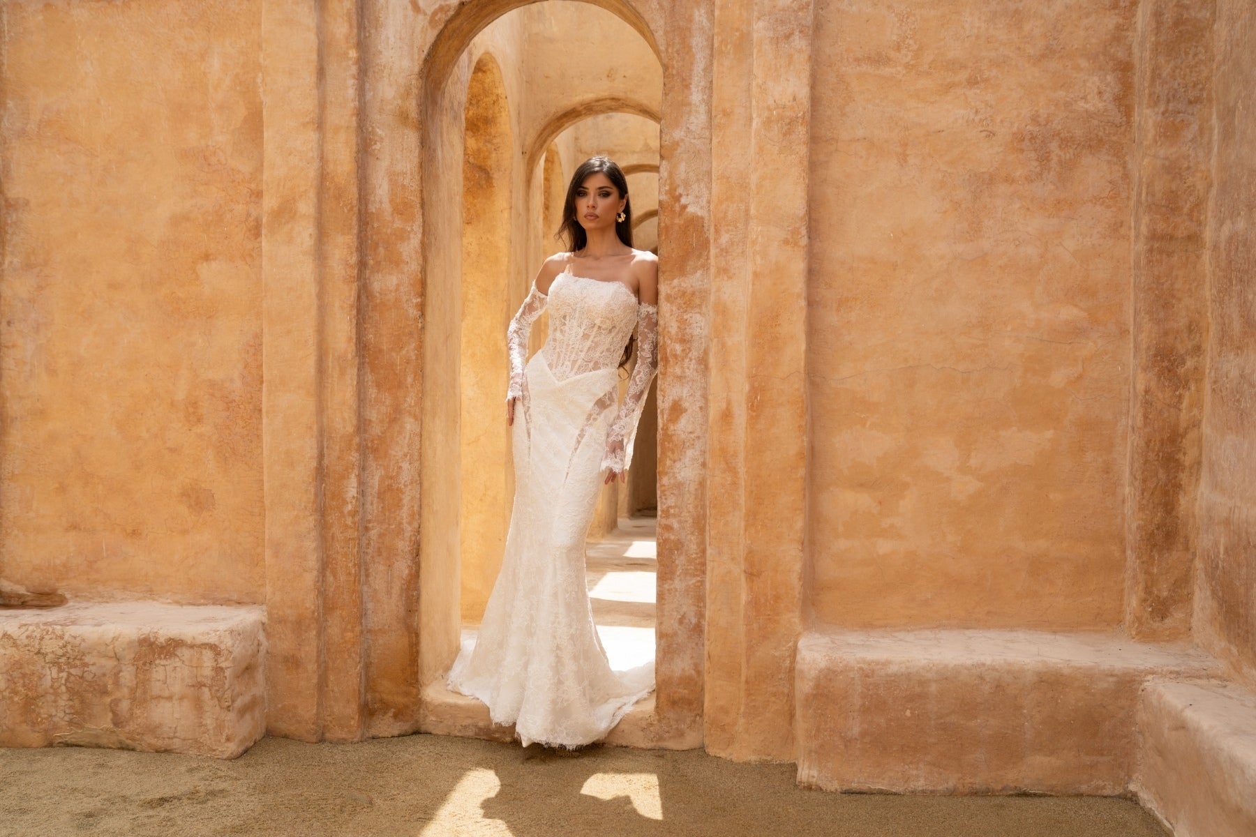 fitted lace wedding dress with basque waist, cat-eye neckline and side cut-outs. paired with fitted lace sleeves. 