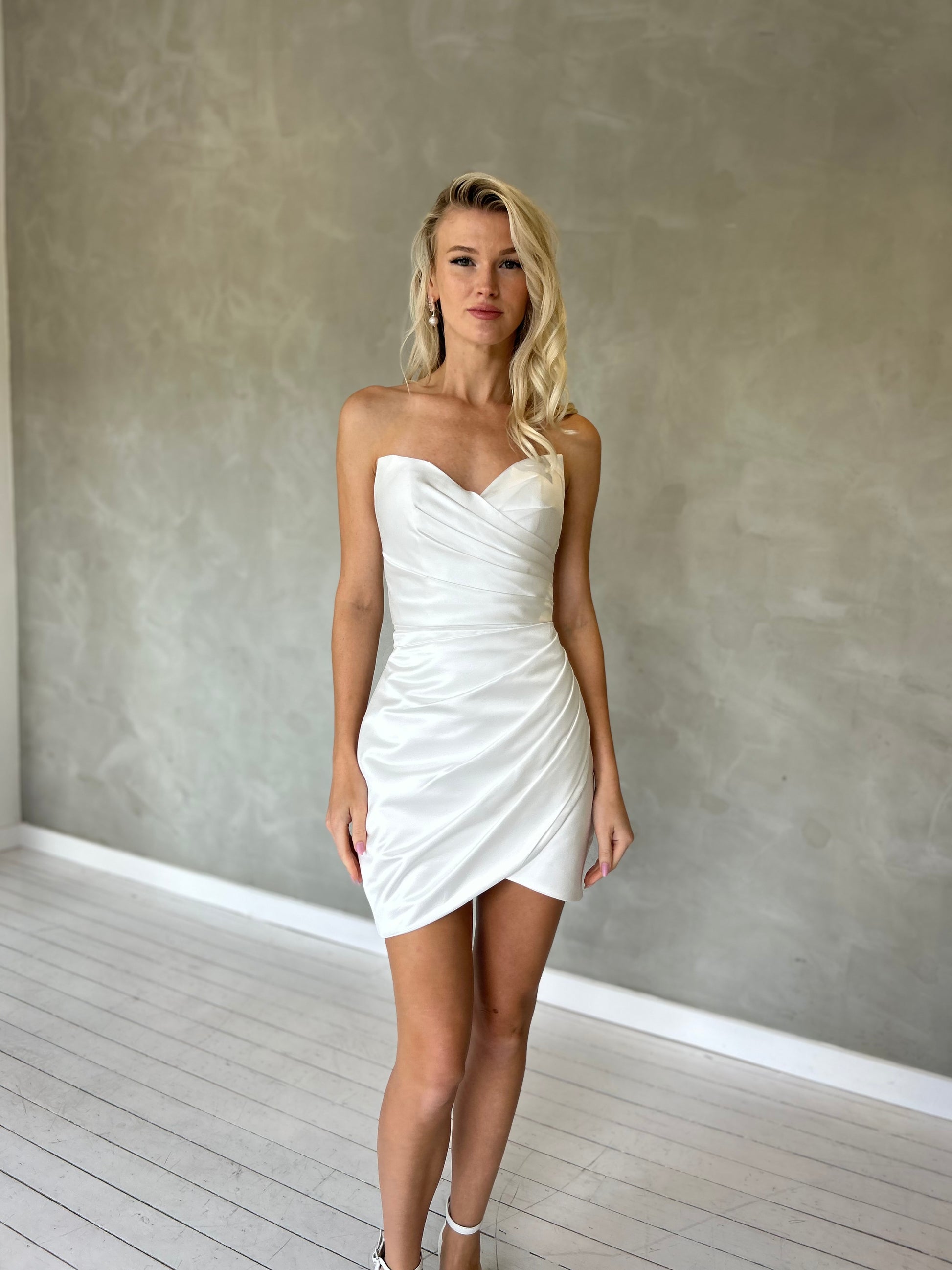 Fitted mini wedding dress in satin fabric, featuring a strapless sweetheart neckline with Ruching 