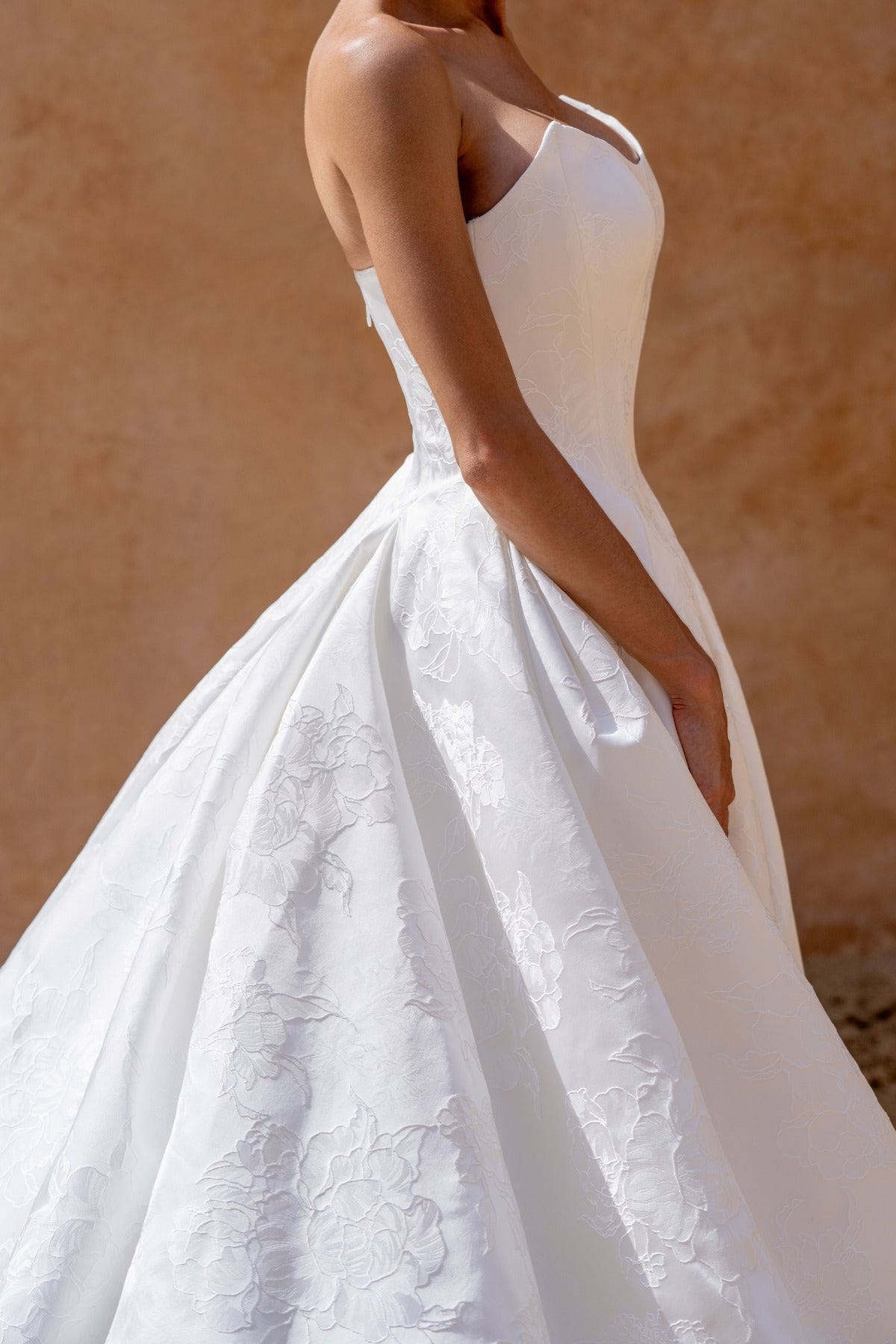 dramatic A-line wedding dress in floral jacquard fabric, featuring a steep basque waist and cat-eye neckline 