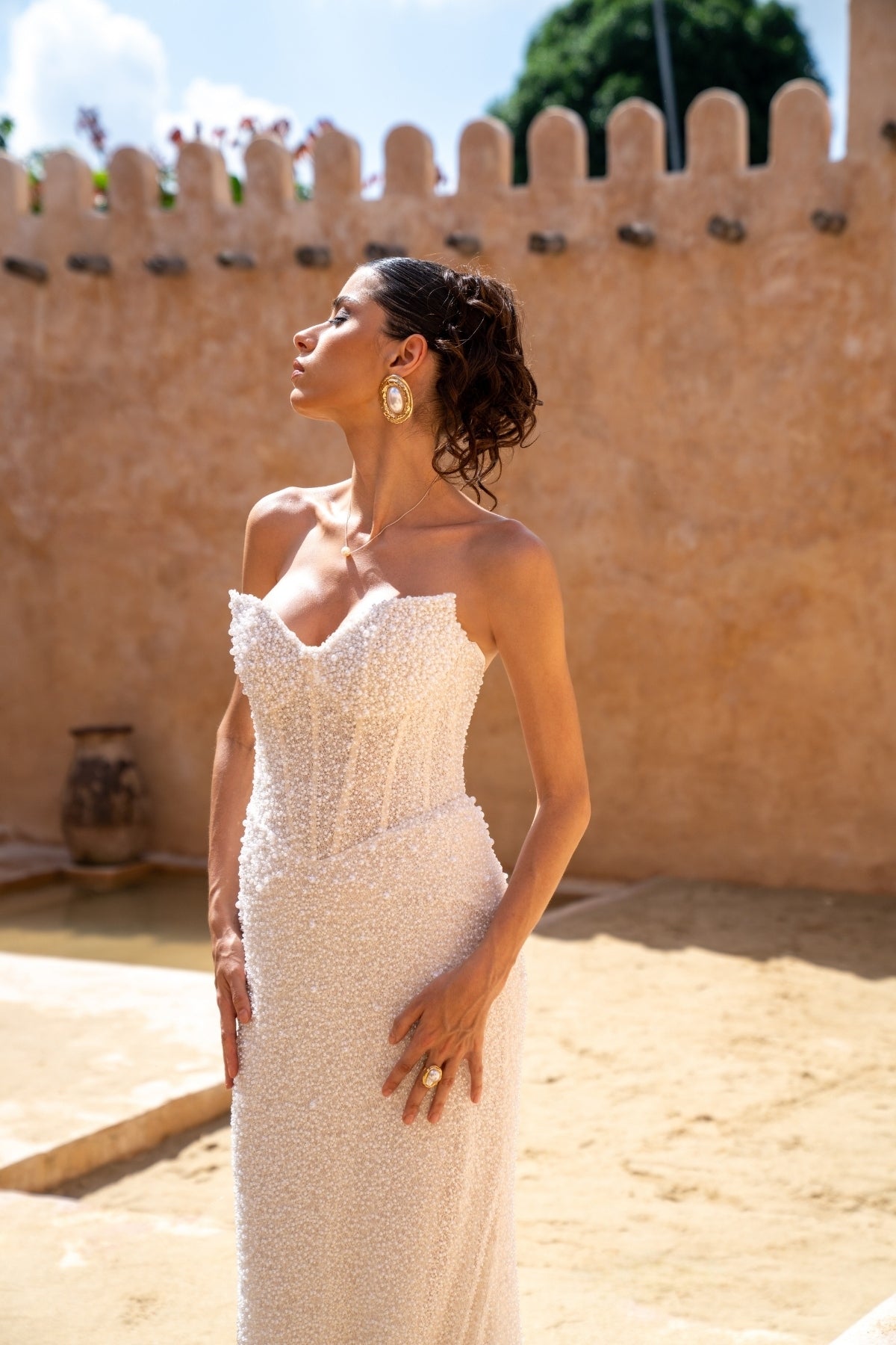 fitted wedding gown with beaded lace, covered in pearls, featuring cat-eye neckline and basque waist. 