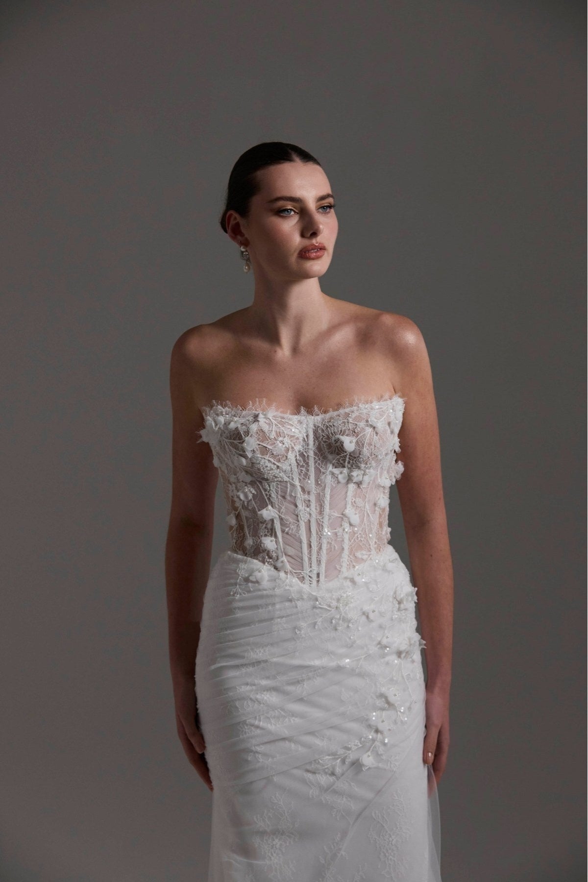 Fitted Bridal gown with floral lace scattered around the corseted bodice, basque waistline. 