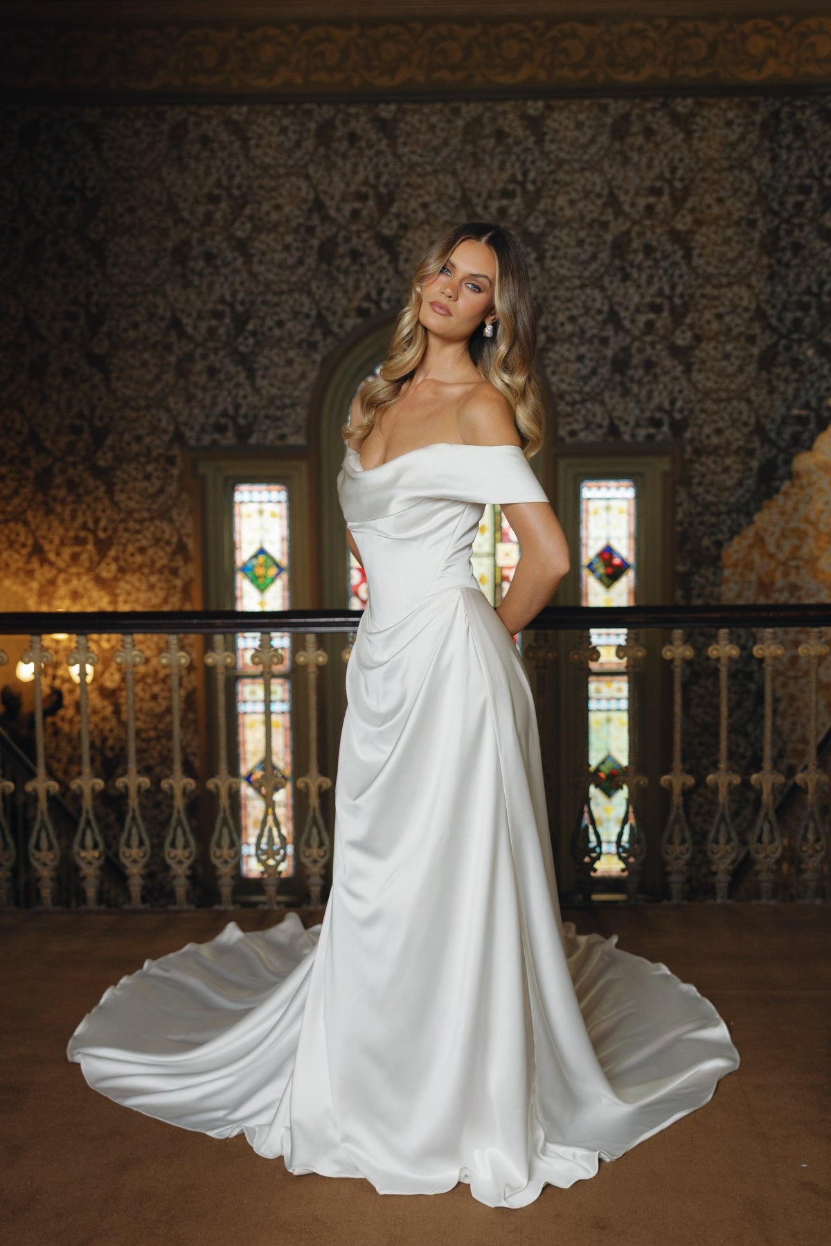 A satin sheath fit wedding gown featuring off the shoulder neckline and cap sleeves. 