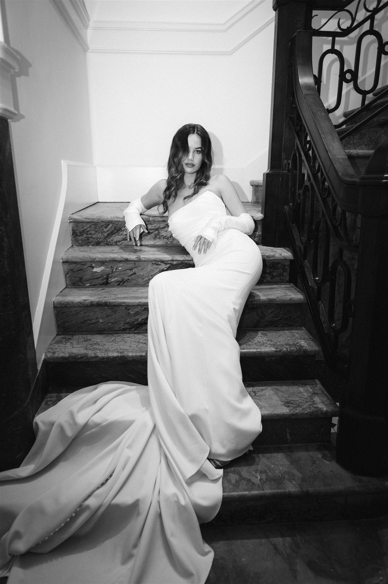 Model sits on stairs in strapless Tina gown and separate ivory mikado sleeves