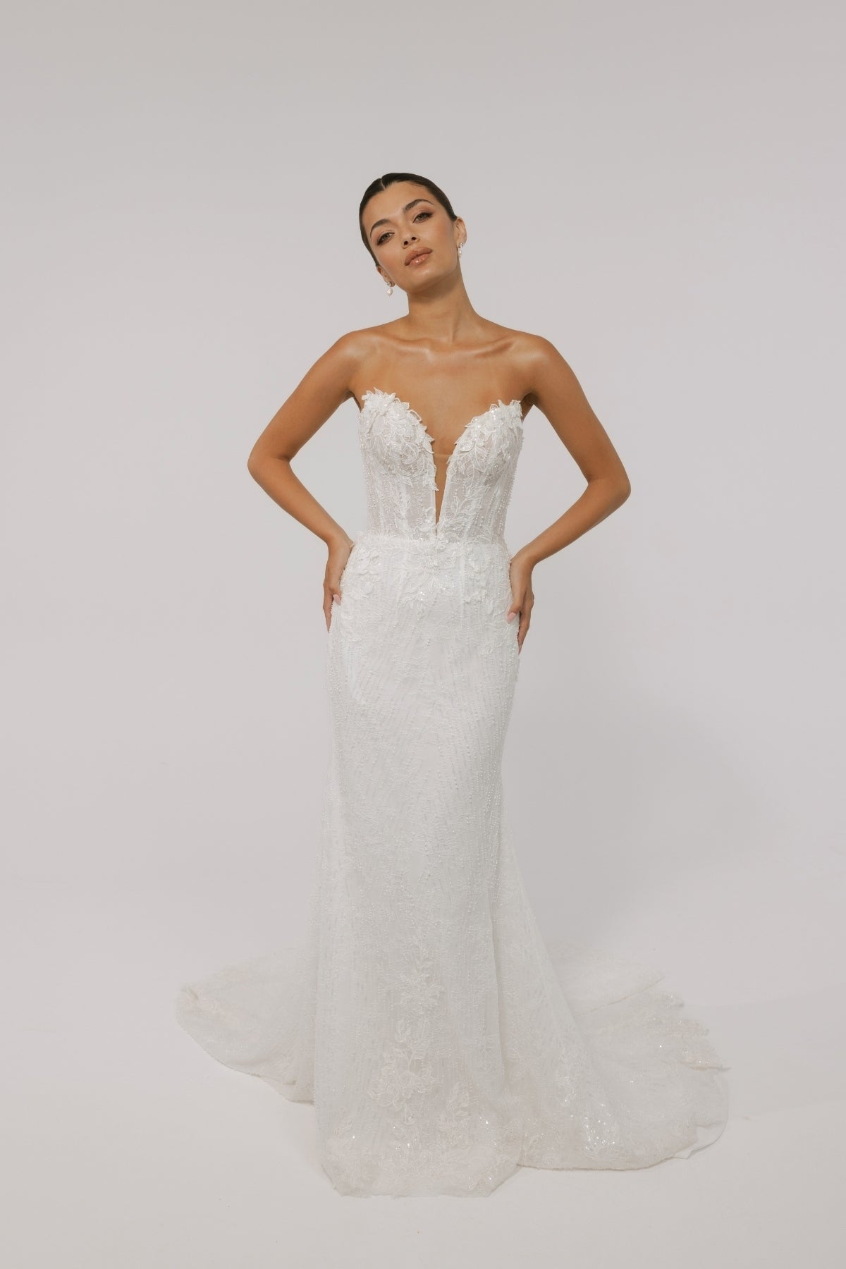 Fitted wedding gown with a deep v plunge, strapless neckline, beaded lace. 