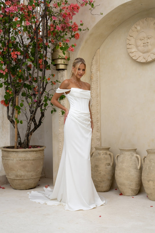 fitted wedding gown with ruched bust, corset boning, and draping across the hips. paired with detachable off the shoulder cap sleeves with pearls. plain fabric, minimal vibes. 
