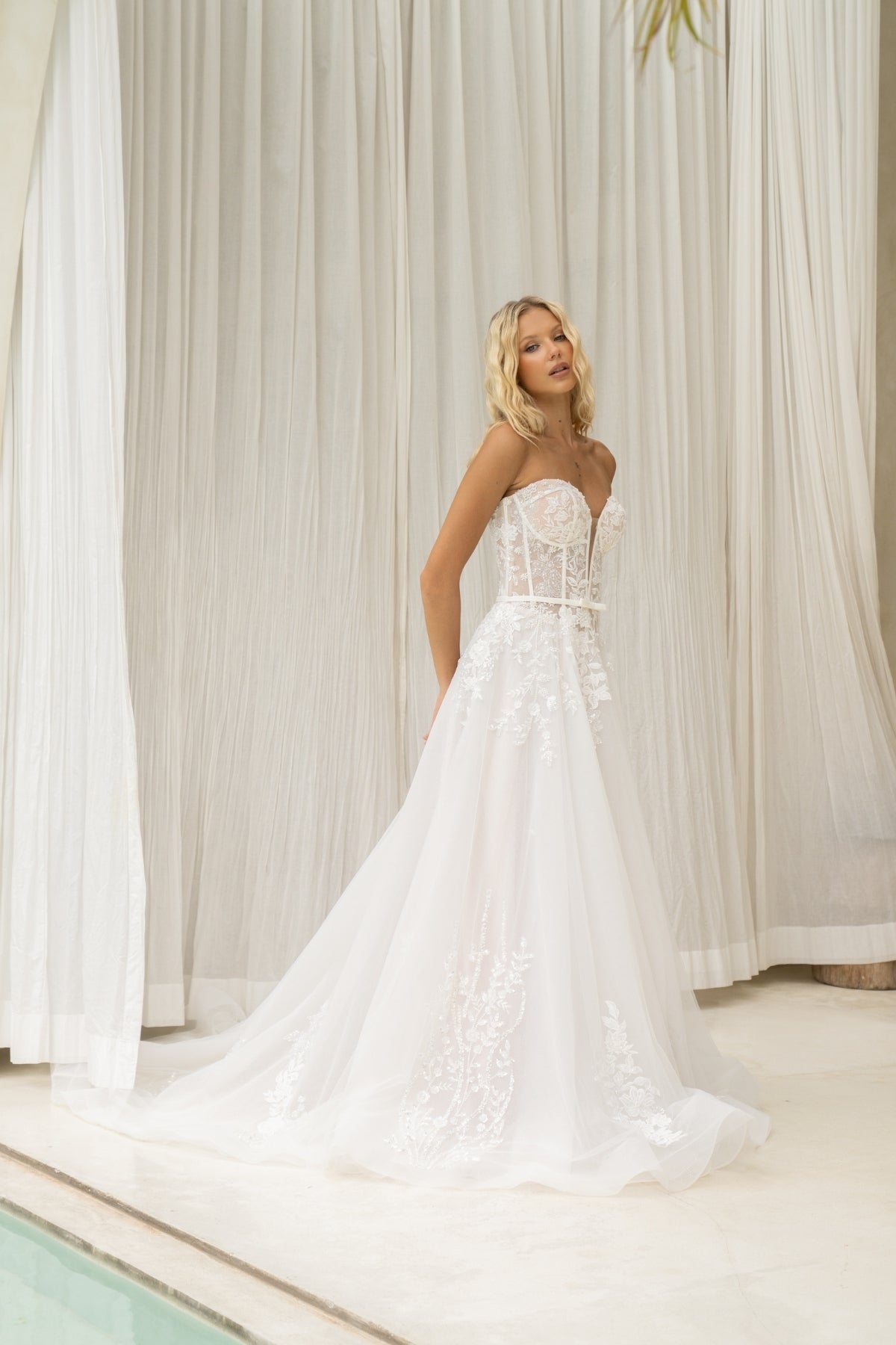 A-line wedding dress with v-plunge sweetheart neckline, floral lace, waistbelt and subtle basque waist, flowing tulle skirt. 