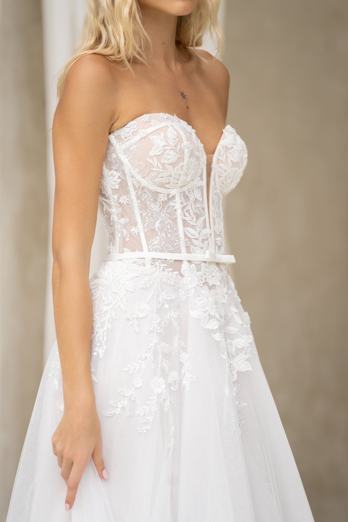 A-line wedding dress with v-plunge sweetheart neckline, floral lace, waistbelt and subtle basque waist, flowing tulle skirt. 