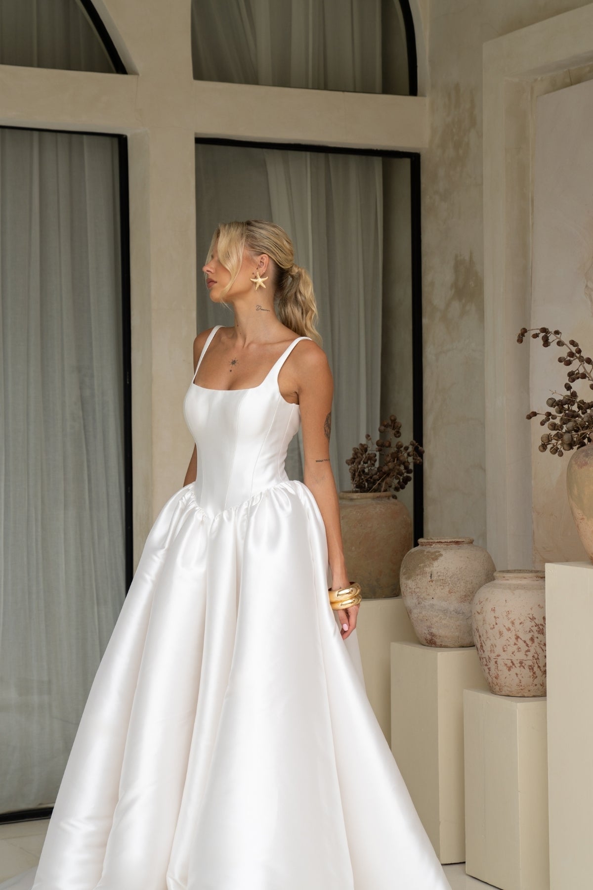 Dramatic A-line wedding gown featuring a squared neckline with straps. subtle basque waist with ruching all around waistline. chapel train. 