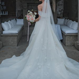 Back view of bride wearing dress with large train and 3D floral veil