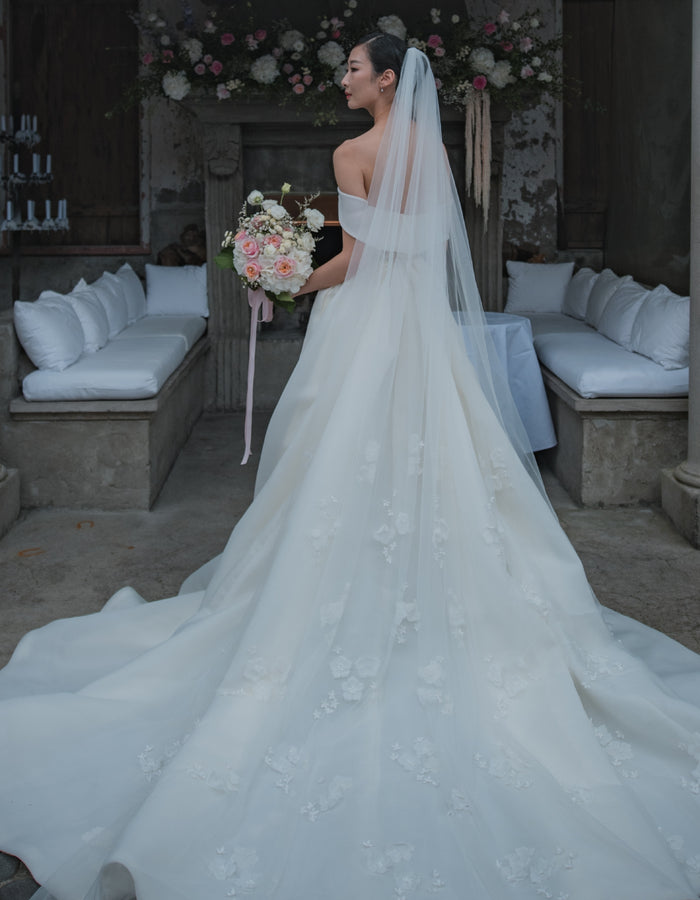 Back view of bride wearing dress with large train and 3D floral veil