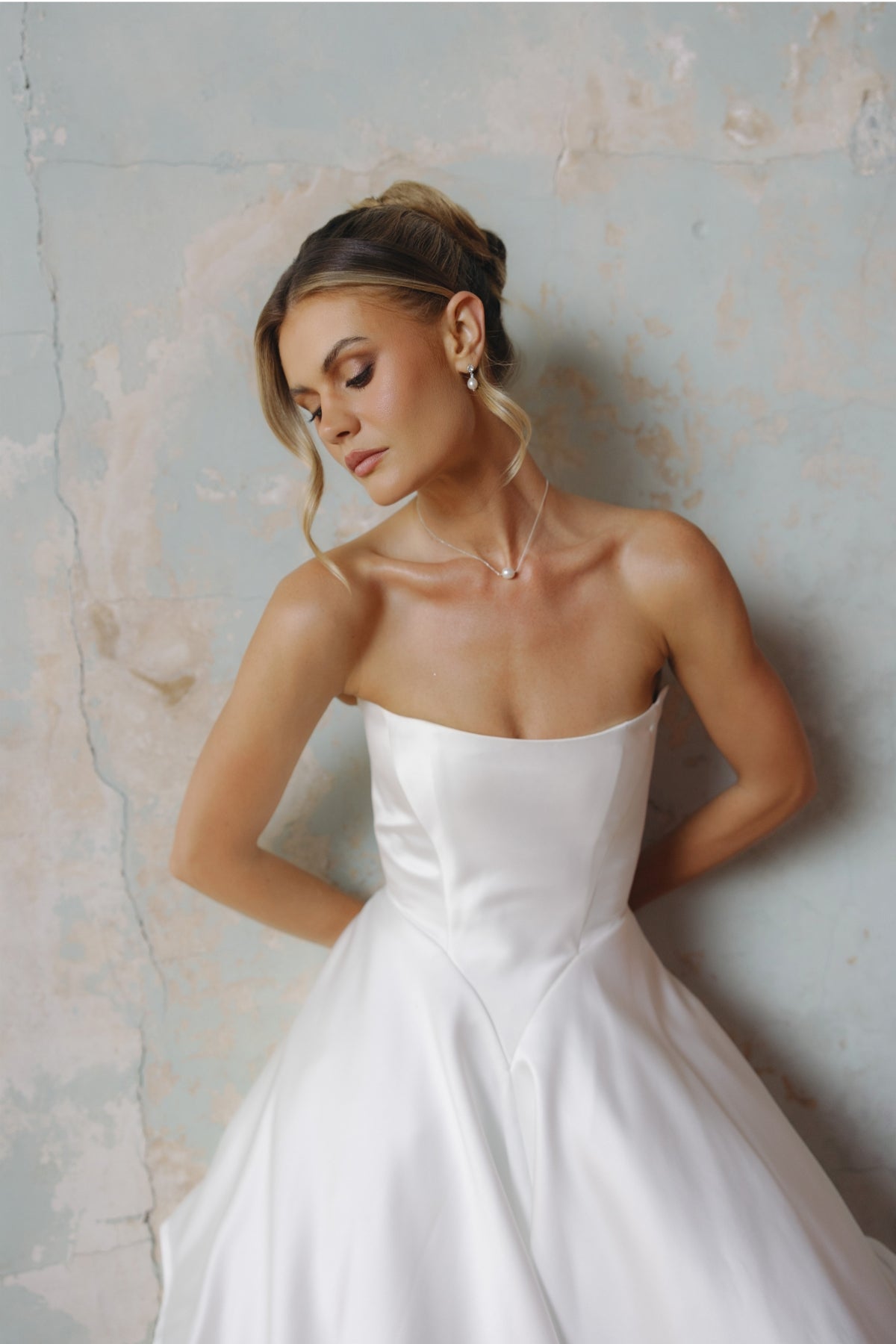 Strapless A-line satin wedding gown featuring cut drapes on the skirt 