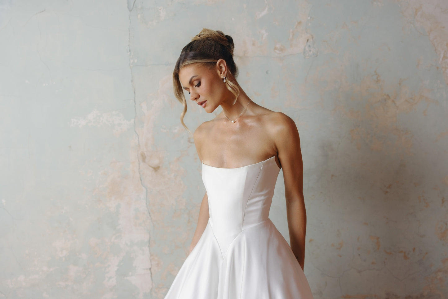Strapless A-line satin wedding gown featuring cut drapes on the skirt 