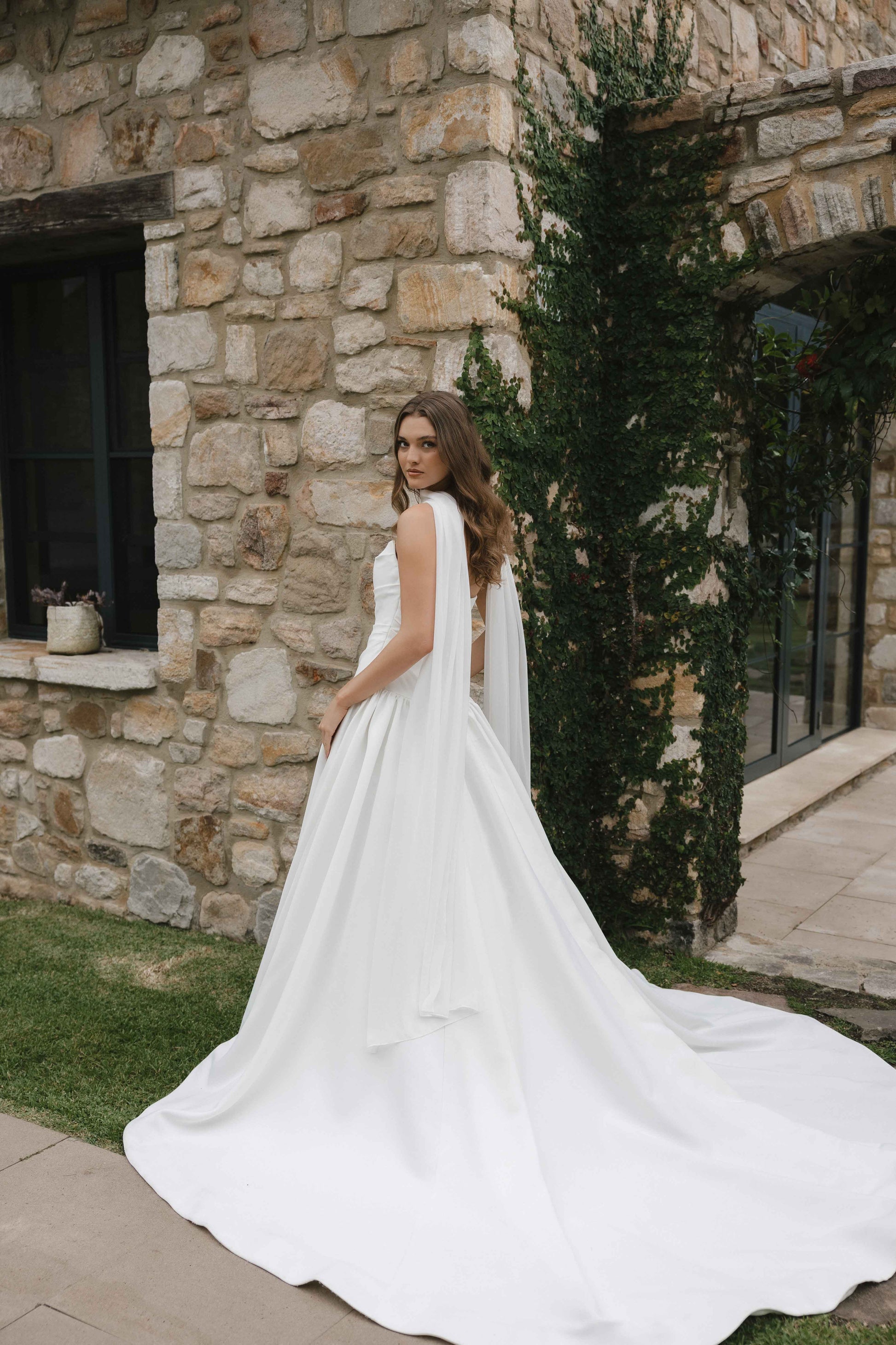 Jana Gown – A-line drop-down waist silhouette with a cat-eye bodice and draped ruching, paired with the Tonica scarf. By Roselle Collection, Jessica Couture.