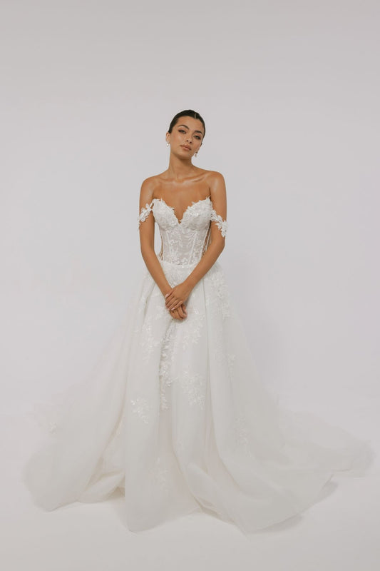 wedding dress featuring off the shoulder straps, sweetheart neckline, sheer boning on the sides, and floral lace A-line skirt 