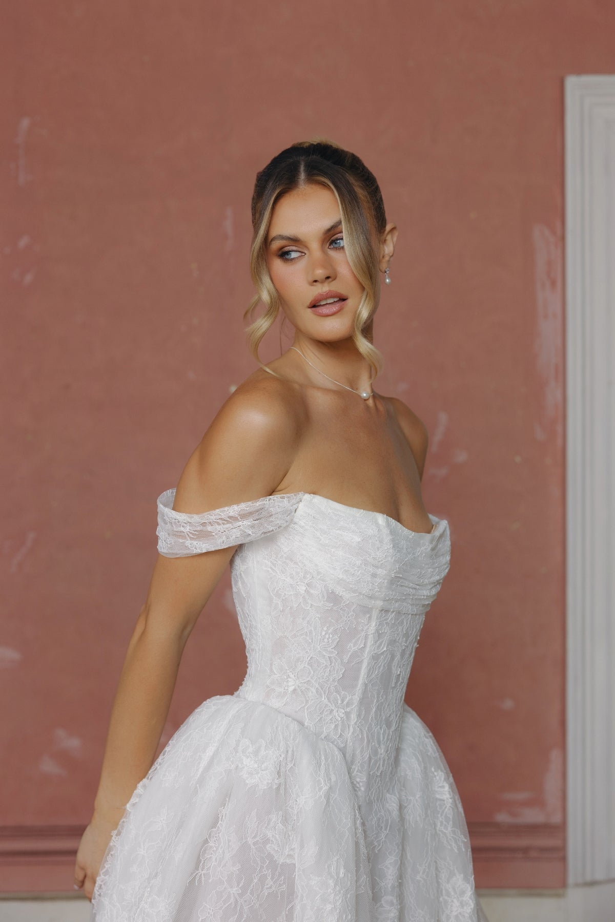 off the shoulder A-line wedding gown in lace, steep basque waist and ruched bust. 
