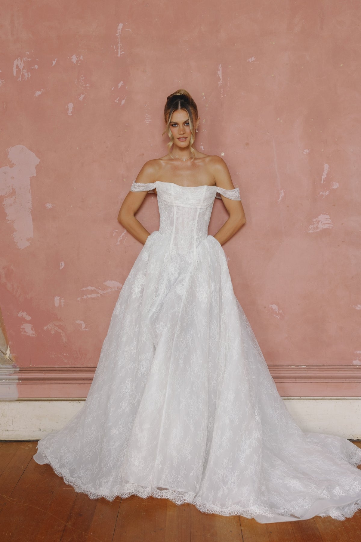 off the shoulder A-line wedding gown in lace, steep basque waist and ruched bust. 